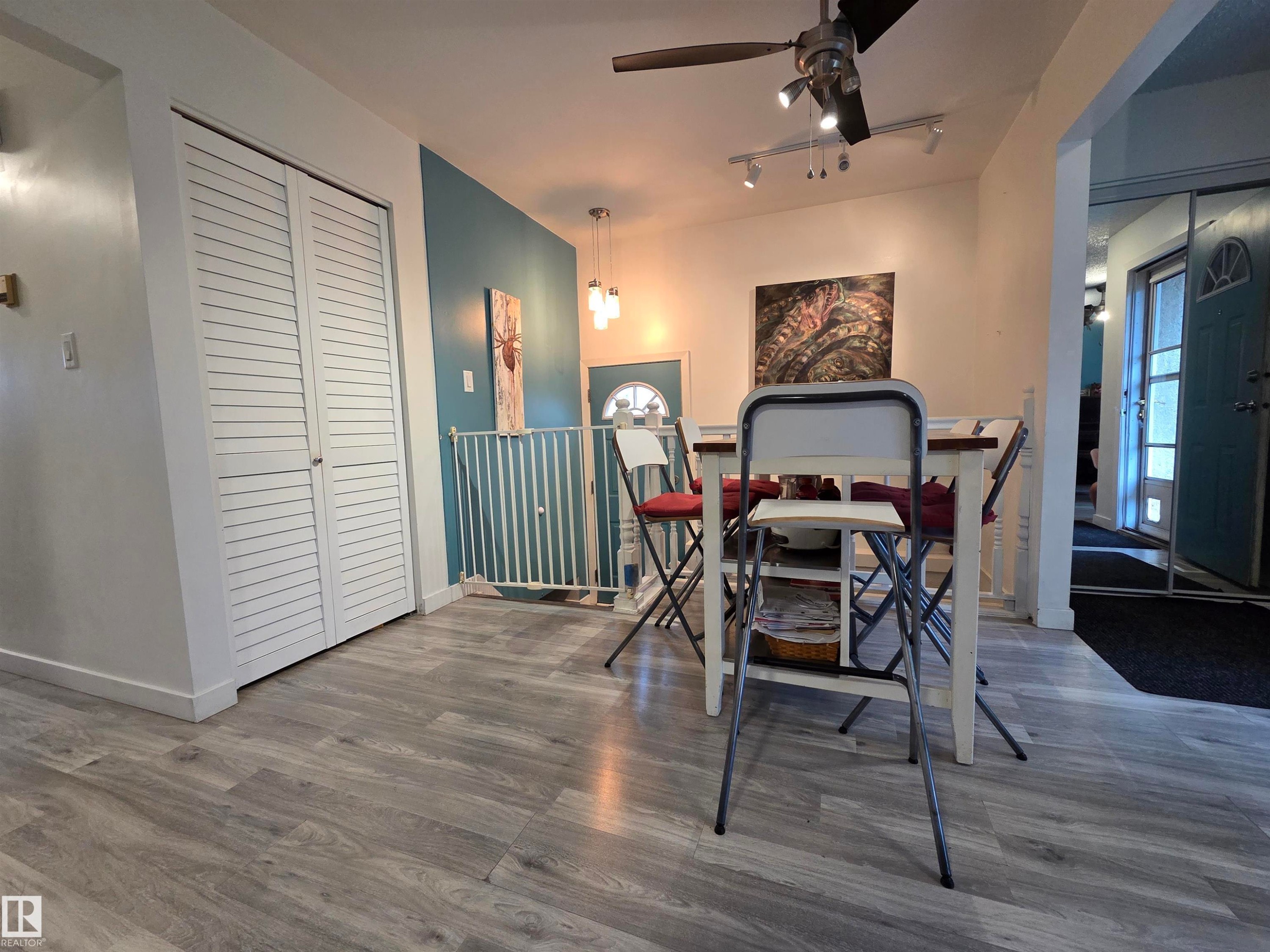 Open-concept dining area featuring wood-finish flooring, a contemporary ceiling fan, track lighting, and a modern pendant light fixture - 2514 149 Avenue, Edmonton, AB