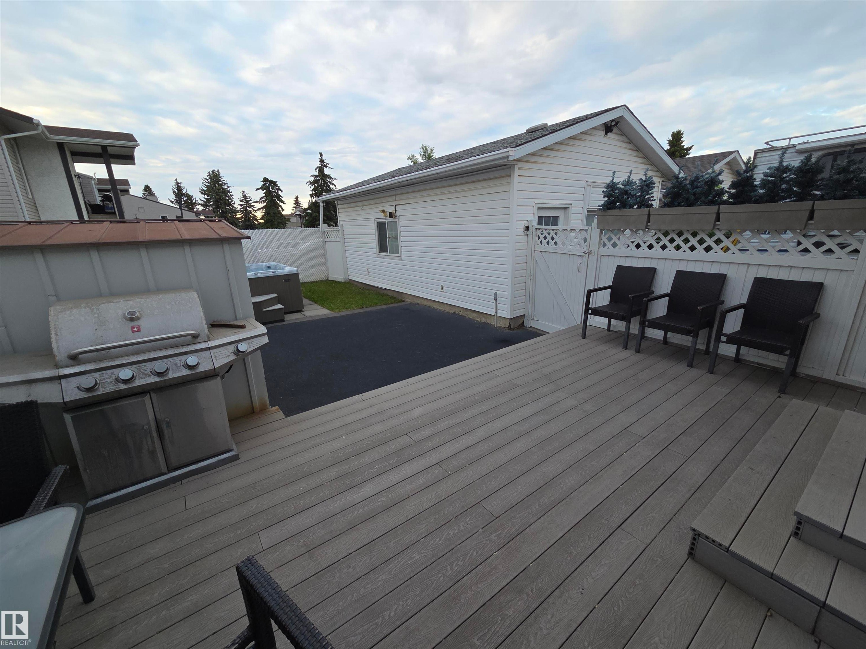 Expansive outdoor living area featuring a multi-level composite deck, white lattice privacy fence, and hot tub with exterior steps - 2514 149 Avenue, Edmonton, AB