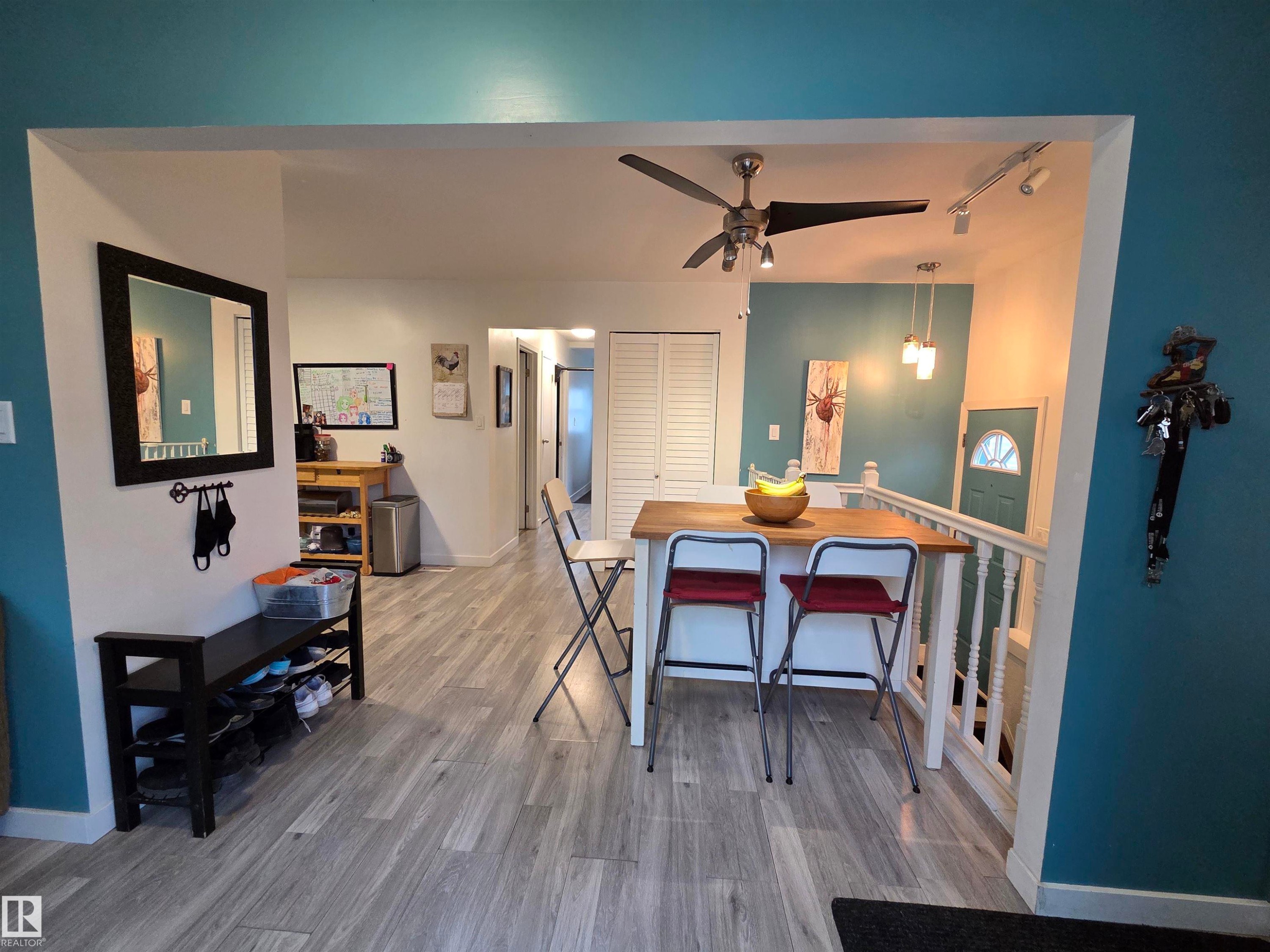 Open-concept living space featuring wood-finish flooring, a contemporary ceiling fan, and track lighting - 2514 149 Avenue, Edmonton, AB