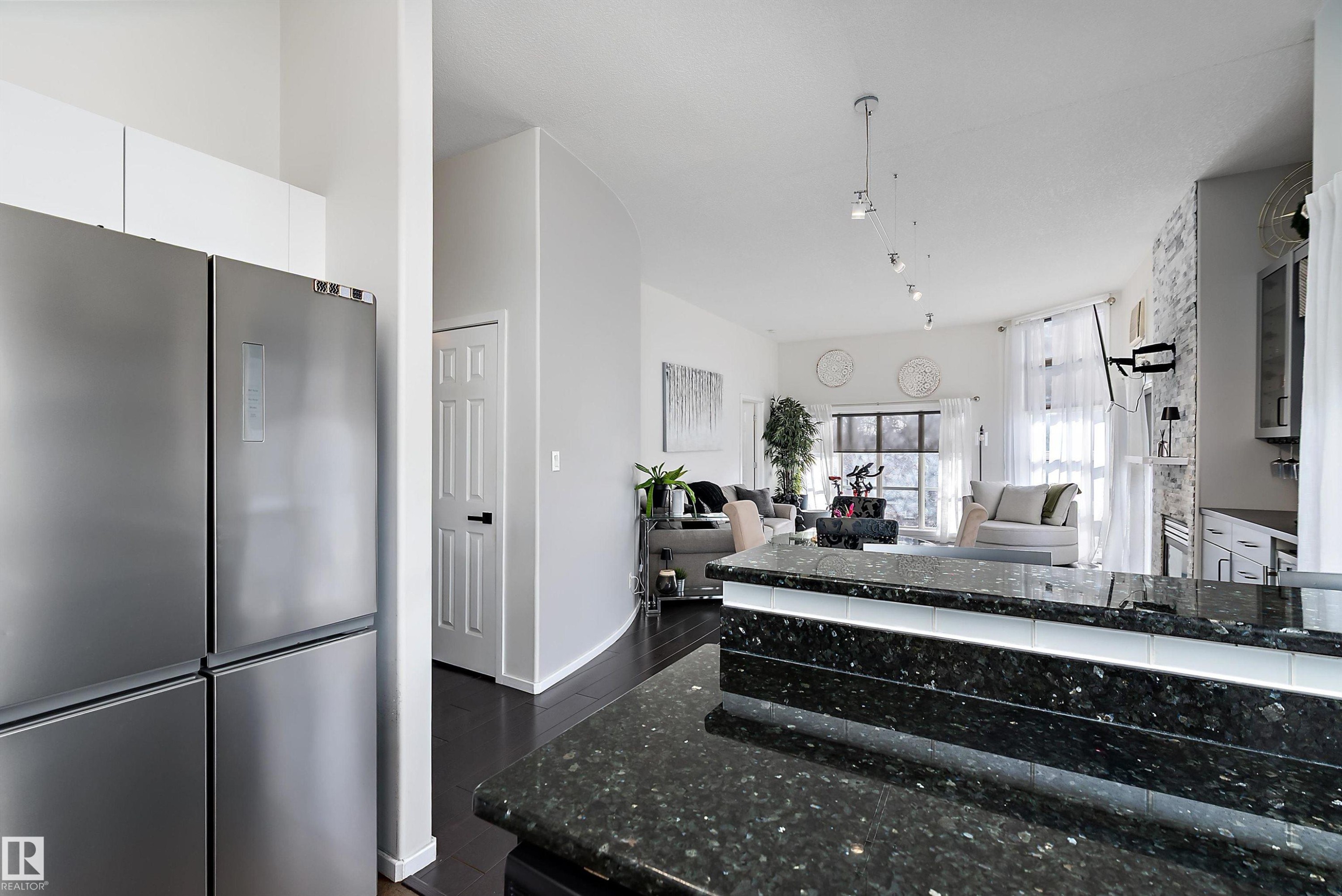 Recently renovated kitchen featuring freestanding refrigerator, dark wood-style floors, open floor plan, and white cabinets - 302 10905 109 Street, Edmonton, AB