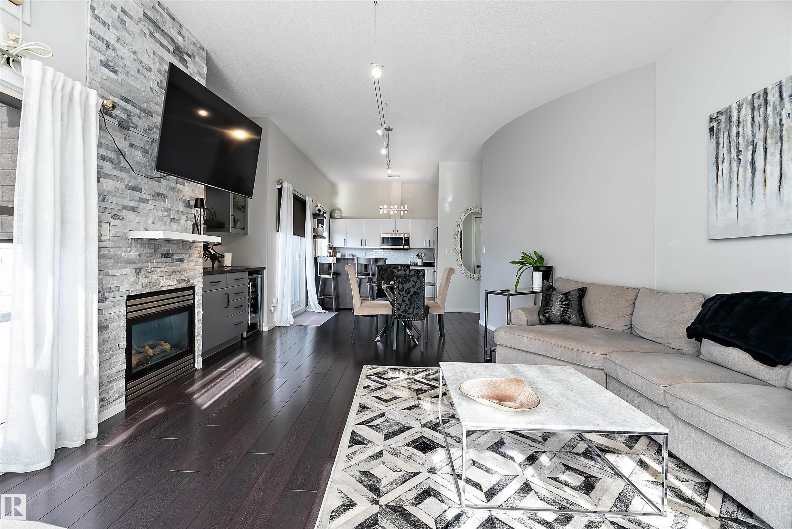 Living room featuring dark wood-type flooring and a stone fireplace - 302 10905 109 Street, Edmonton, AB