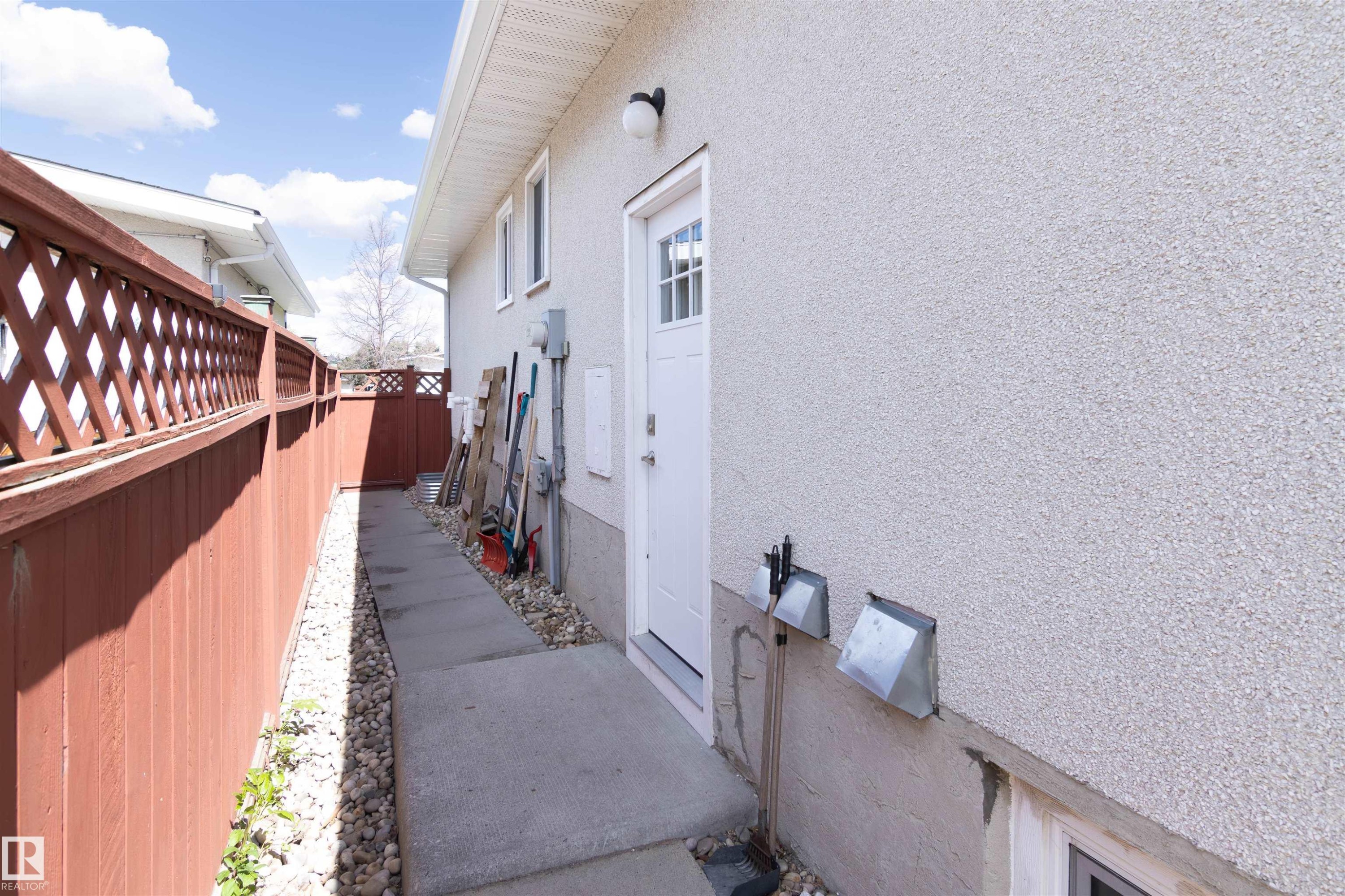 White stucco exterior with a side entry door featuring a glass-paned insert - 7115 39A Avenue, Edmonton, AB - Outdoor With Exterior