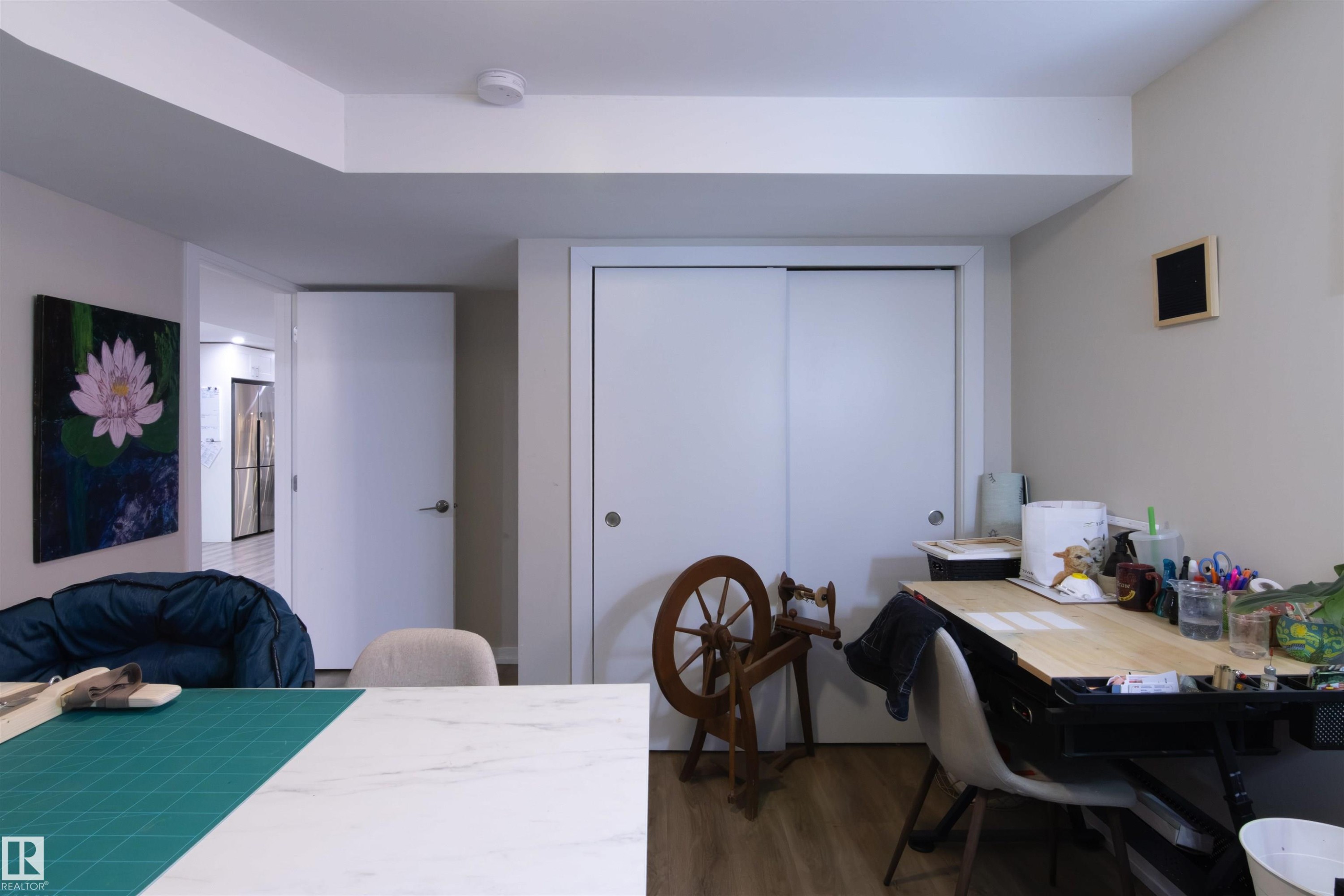 Recessed lighting illuminates an interior room featuring wood-finish flooring, a white sliding closet door, and a white interior door - 7115 39A Avenue, Edmonton, AB - Indoor Photo Showing Office
