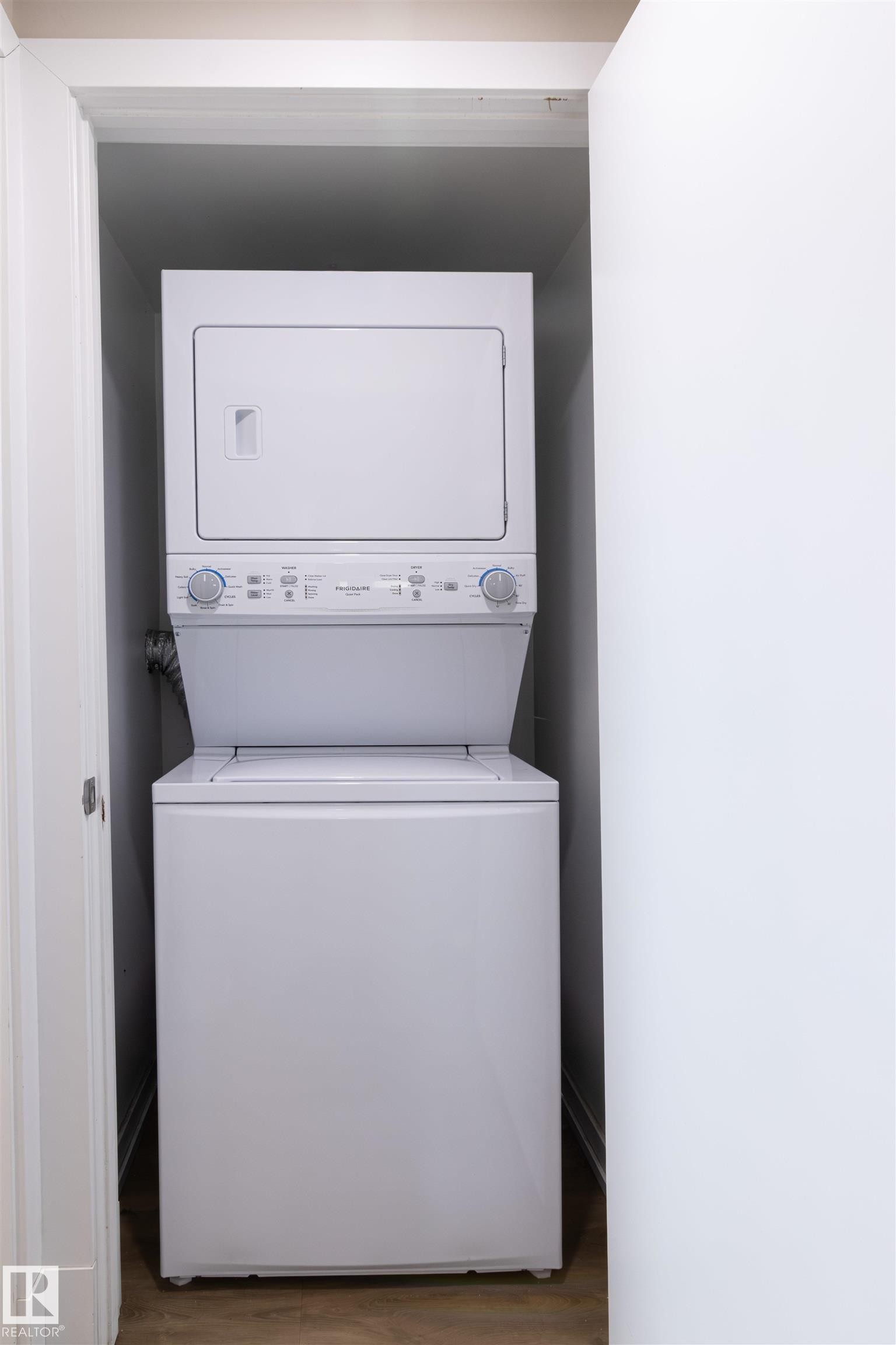 Stacked white laundry appliances within a dedicated utility closet - 7115 39A Avenue, Edmonton, AB - Indoor Photo Showing Laundry Room
