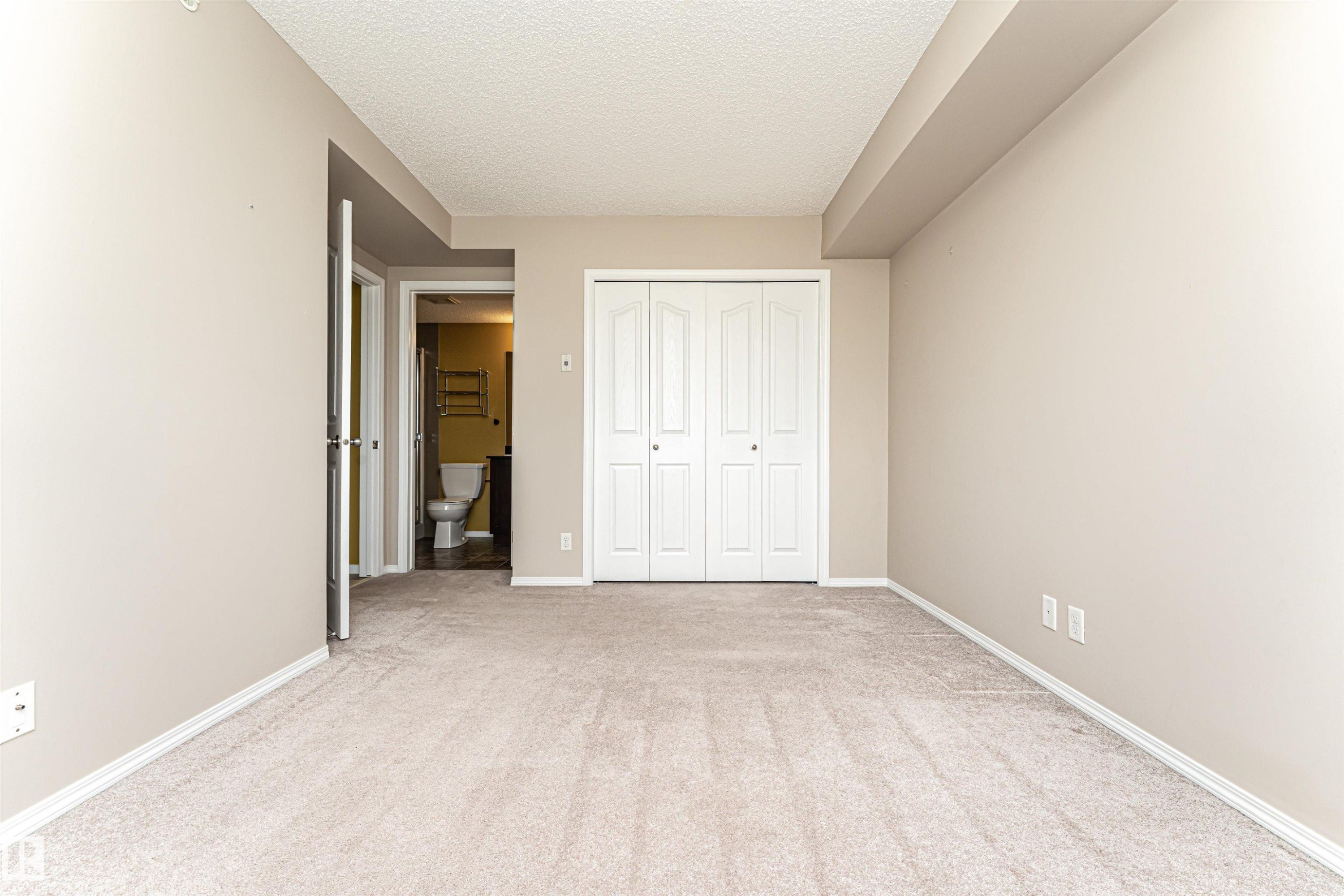Carpeted room with neutral wall paint and white baseboards - 404 12045 22 Avenue, Edmonton, AB