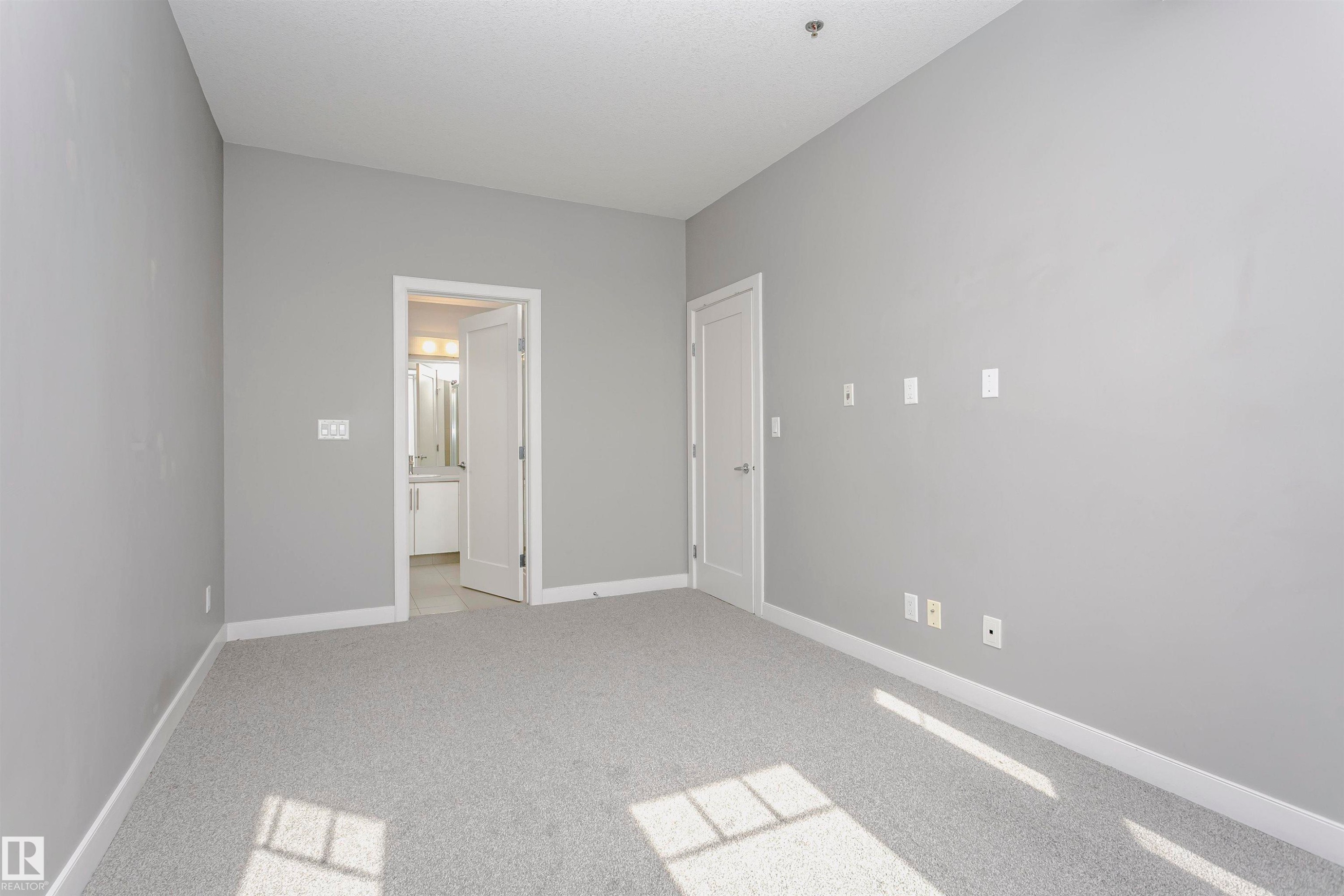 Spacious room featuring light gray carpeting and matching wall tones - 211 10808 71 Avenue, Edmonton, AB