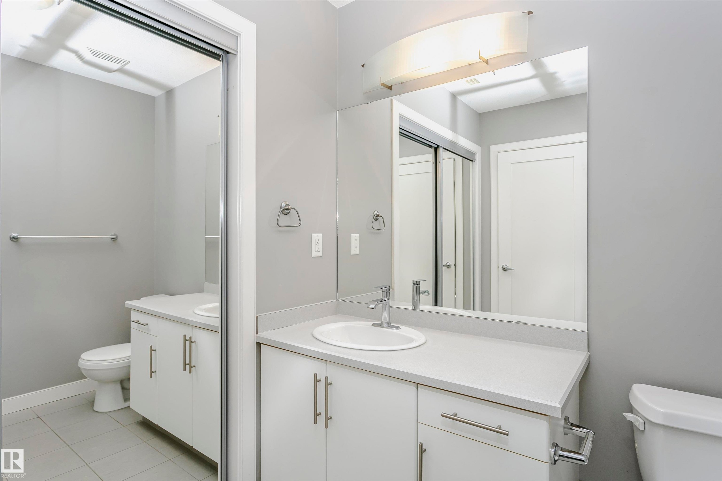 Bright bathroom featuring a dual vanity with white cabinetry, light countertops, and chrome hardware - 211 10808 71 Avenue, Edmonton, AB