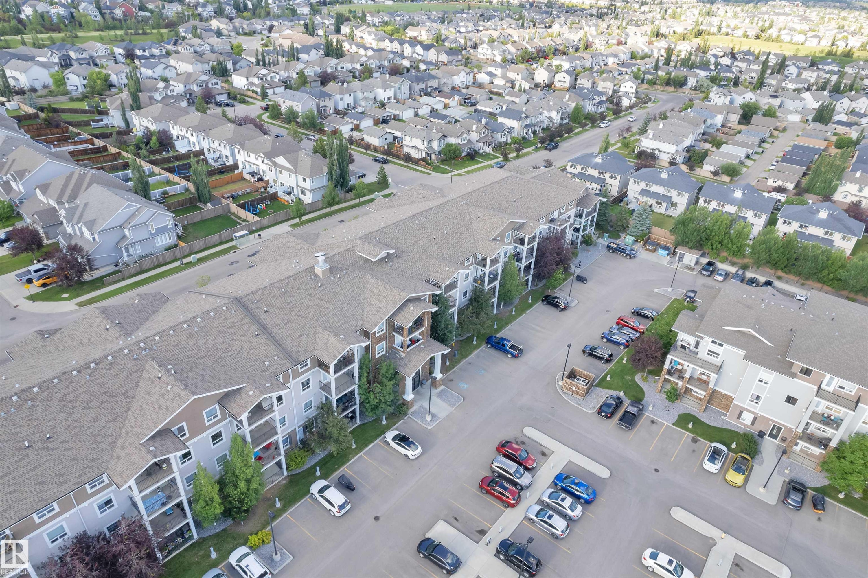 Multi-story apartment building with balconies, exterior siding, and a large parking area - #3302 9351 Simpson Dr Nw, Edmonton, AB