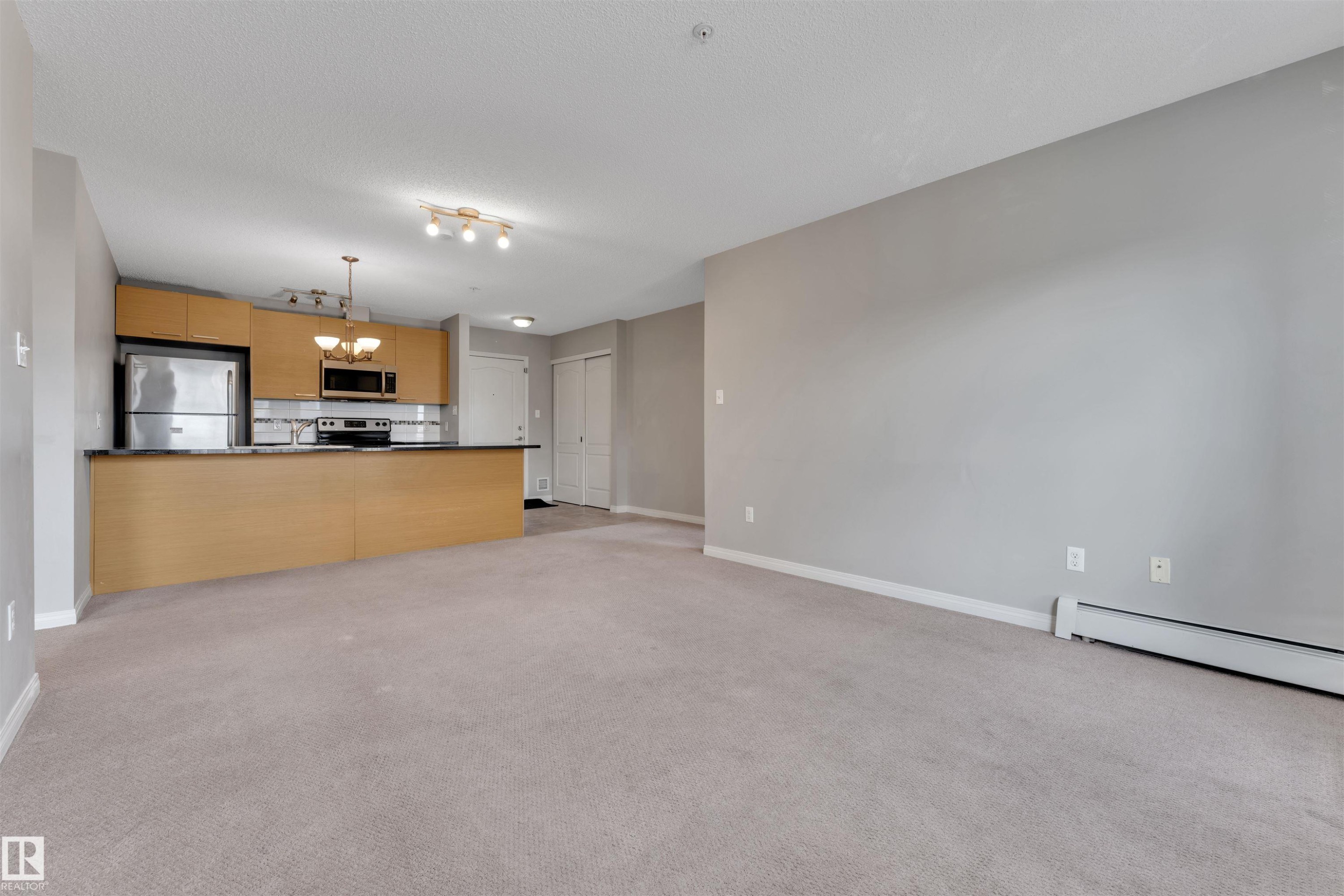 Open-concept living area with neutral carpeting and light gray walls - #3302 9351 Simpson Dr Nw, Edmonton, AB