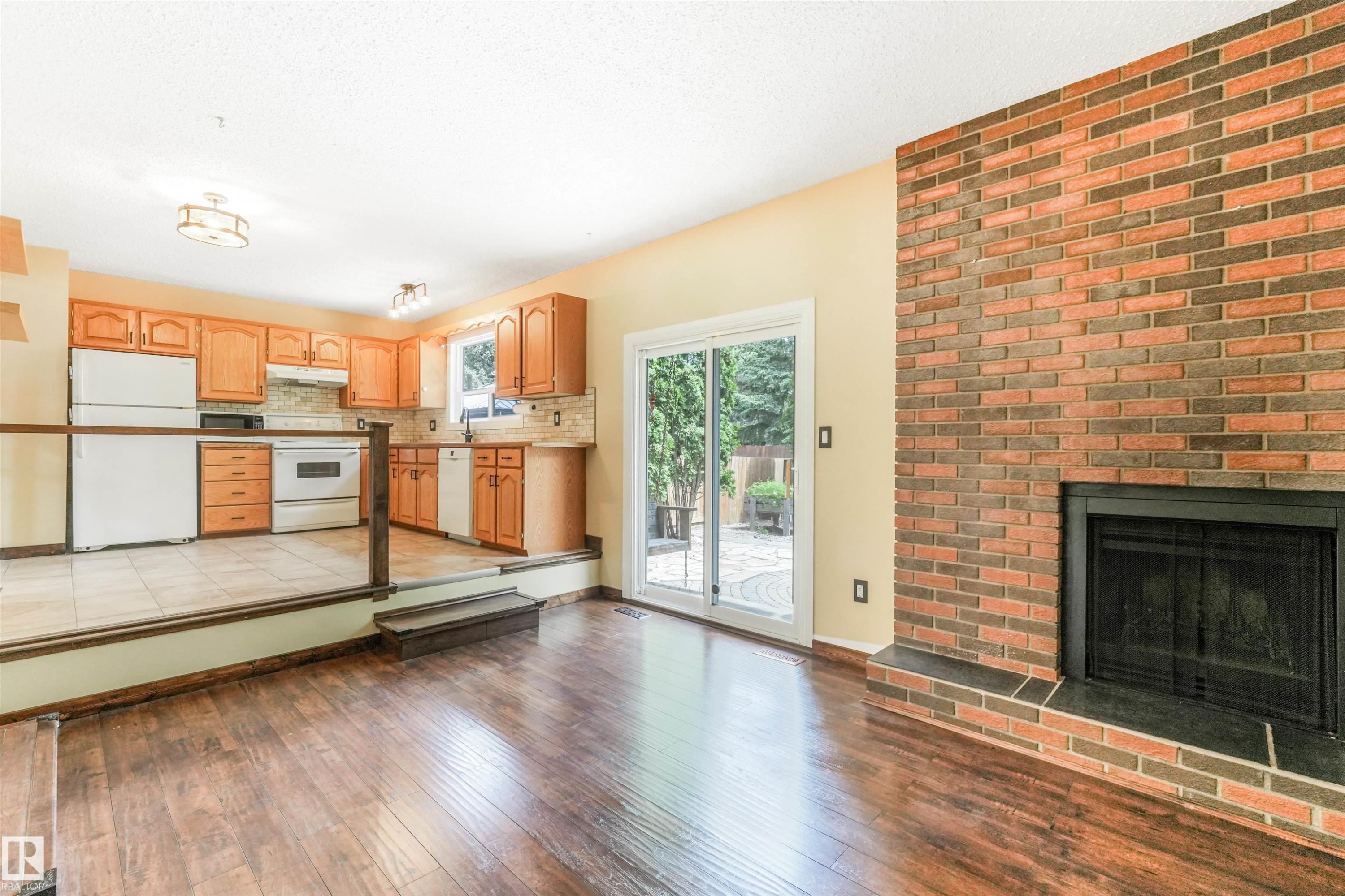 Sunken living room with brick fireplace and sliding patio door to backyard. - 2921 130 Avenue, Edmonton, AB