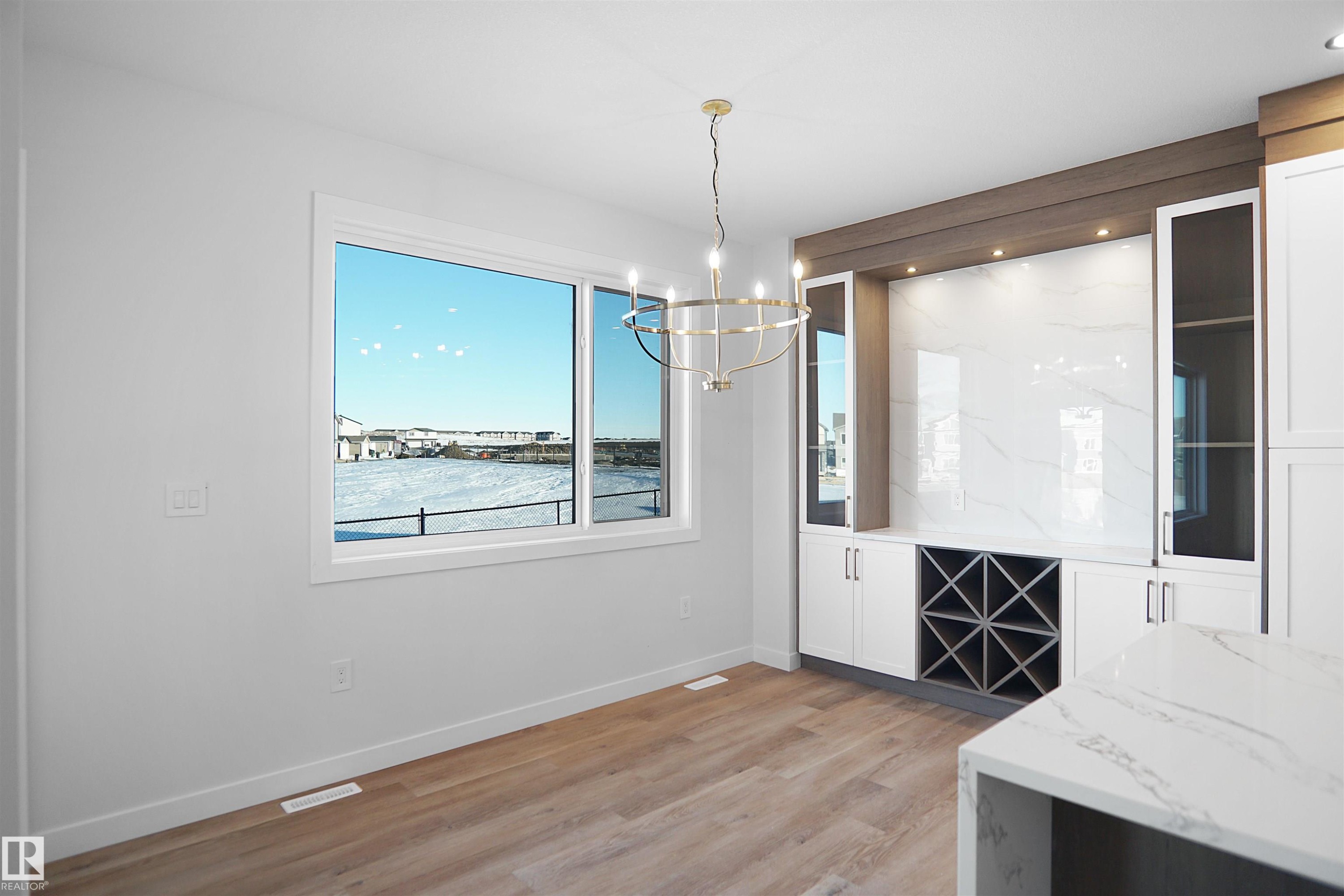 Built-in cabinetry with glass-front display cabinets, integrated wine storage, and a large window providing abundant natural light - 6403 29 Ave, Edmonton, AB - Indoor Photo Showing Other Room