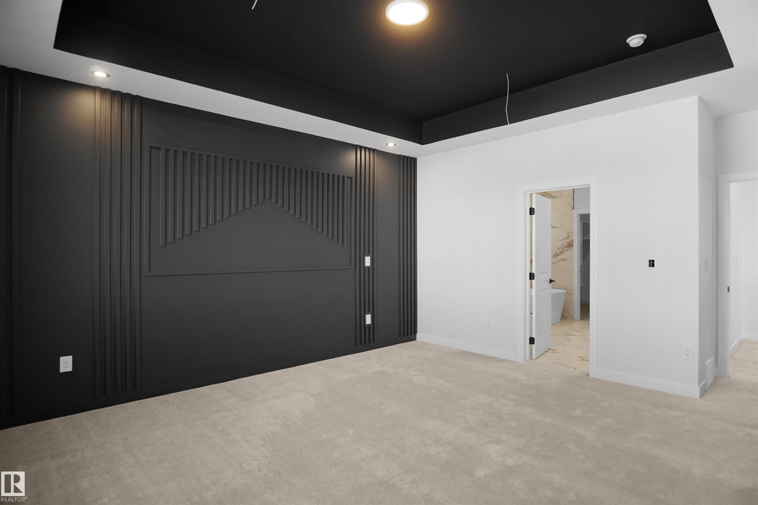 Bedroom featuring a dark accent wall with vertical fluted paneling and geometric detailing, recessed lighting, a dark tray ceiling, and neutral-toned carpeting - 6403 29 Ave, Edmonton, AB - Indoor Photo Showing Other Room