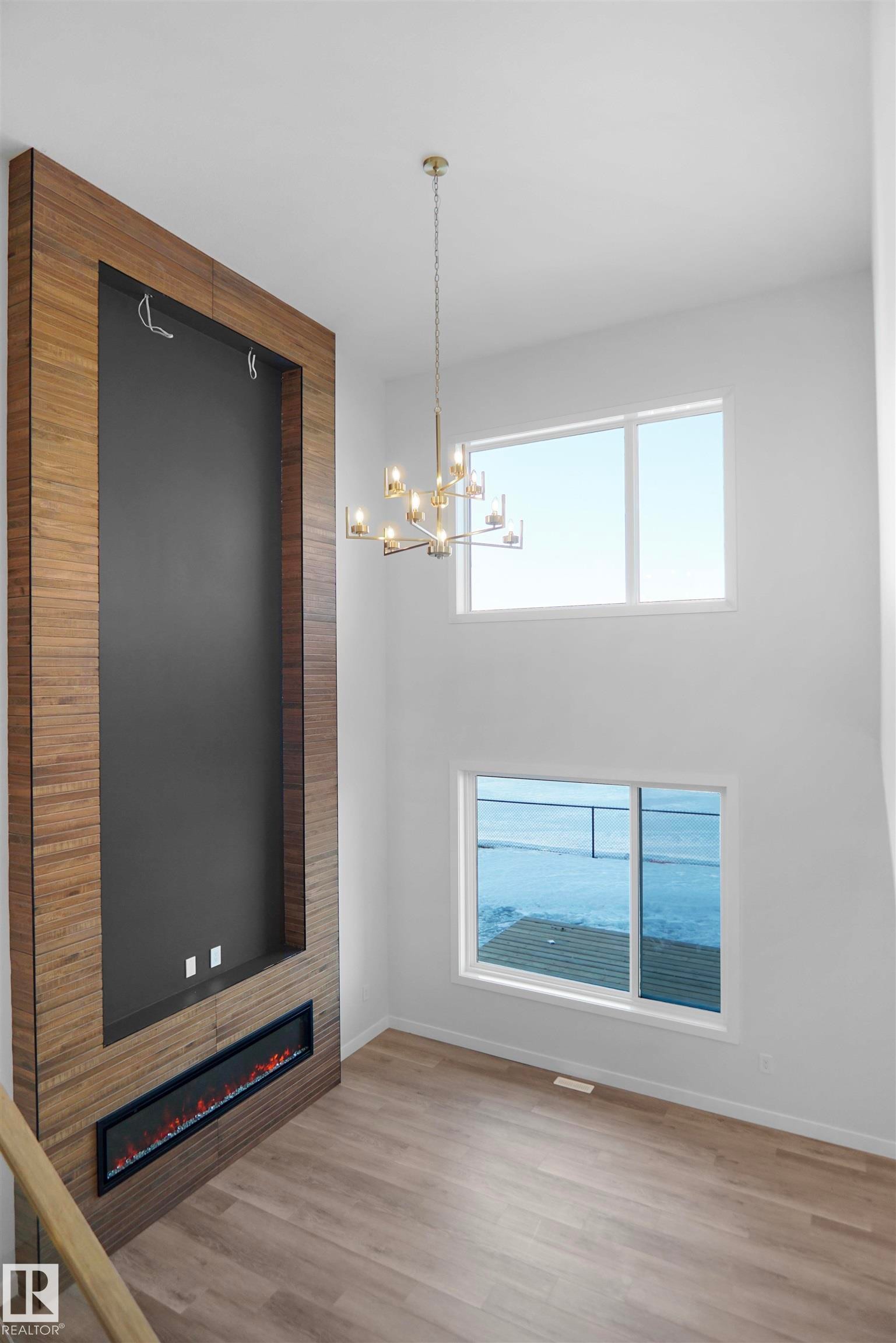 Two-story living area featuring a wood-finish accent wall with an inset electric fireplace - 6403 29 Ave, Edmonton, AB - Indoor Photo Showing Other Room