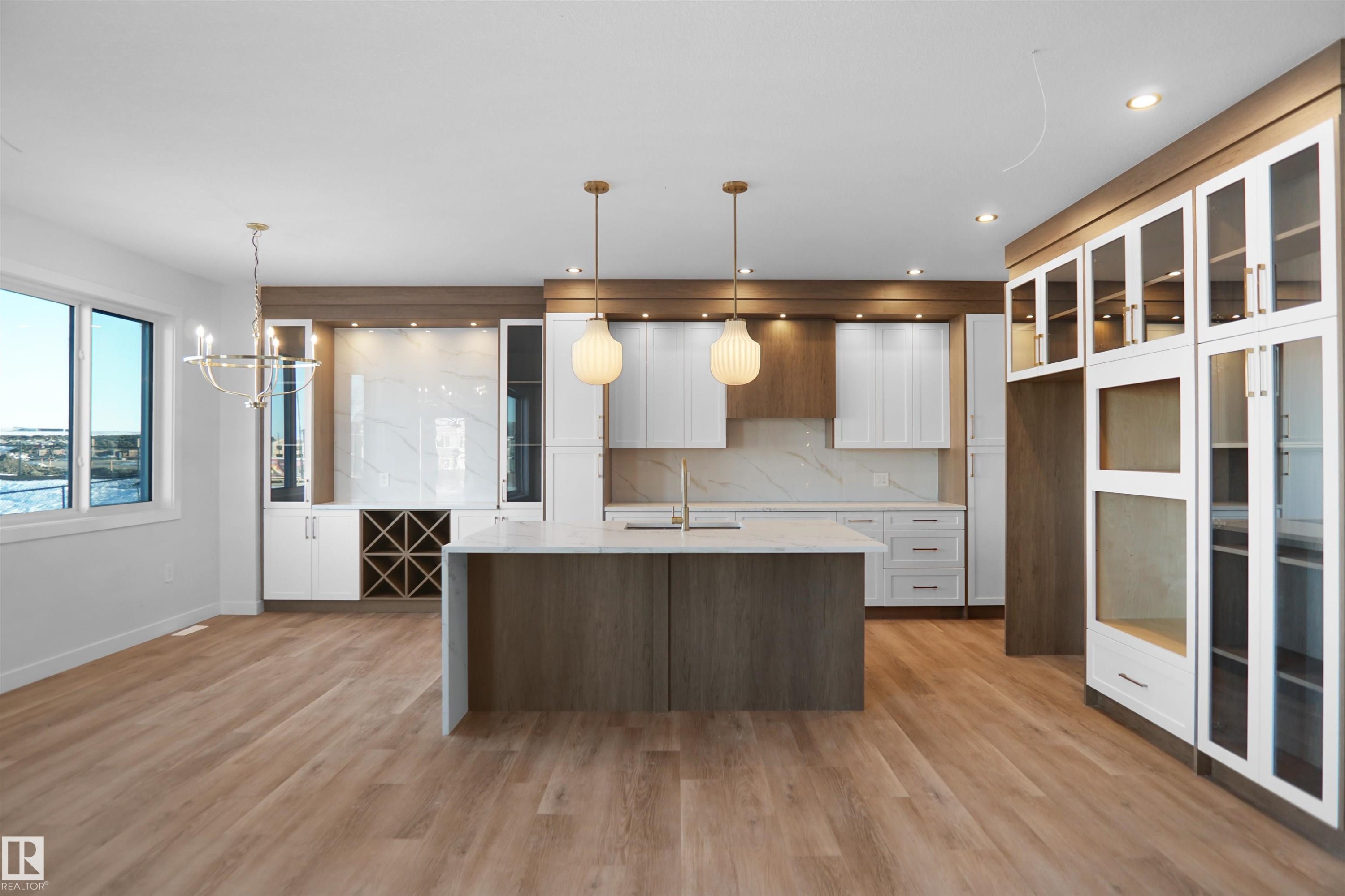 Open-concept kitchen and dining area featuring wood-finish flooring, a central island with a solid surface countertop, white cabinetry, a built-in wine rack, and pendant lighting - 6403 29 Ave, Edmonton, AB - Indoor Photo Showing Kitchen