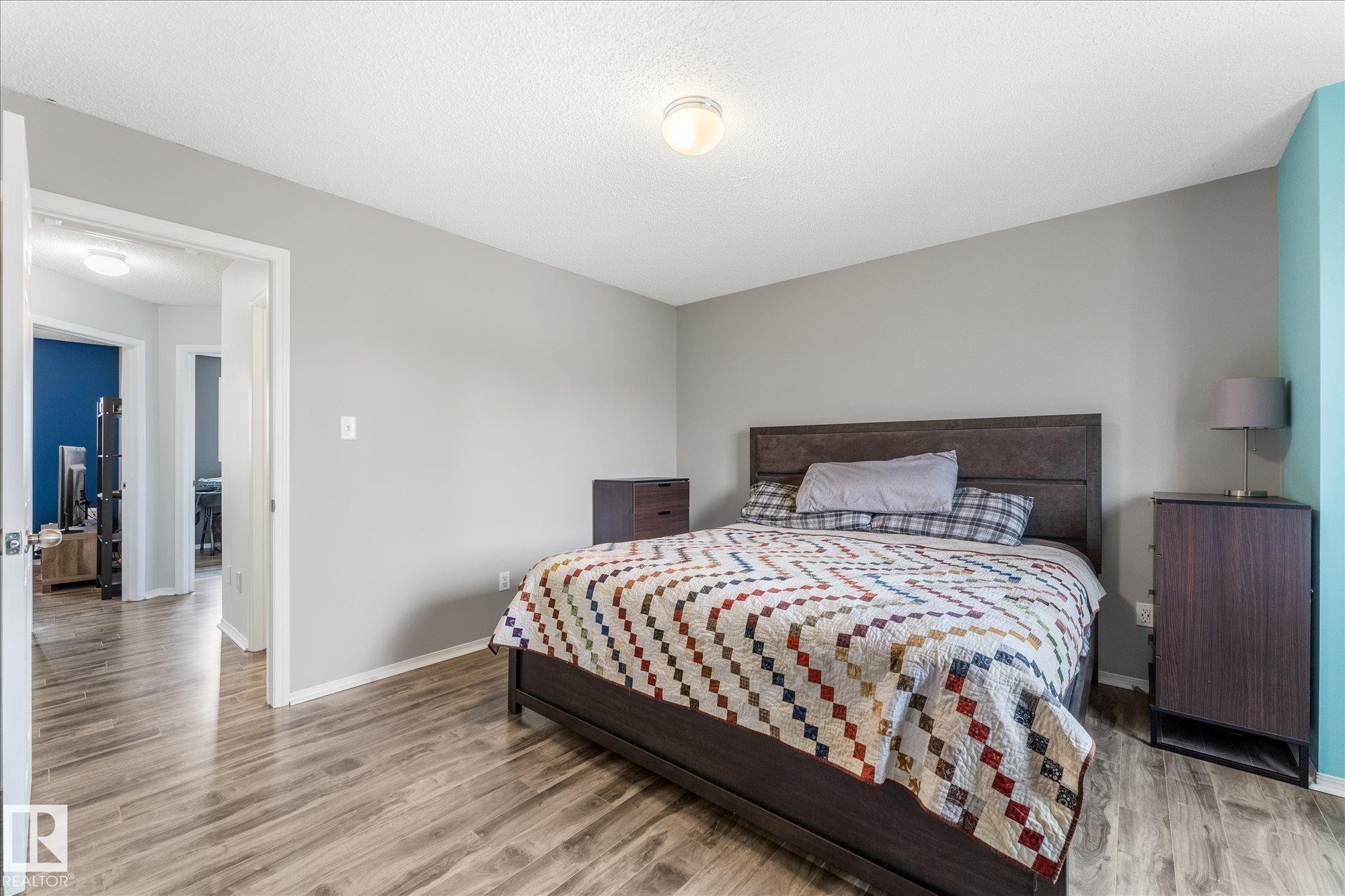 Spacious bedroom featuring wood-finish flooring, light grey painted walls, and a light-colored ceiling - 2324 30 Avenue, Edmonton, AB