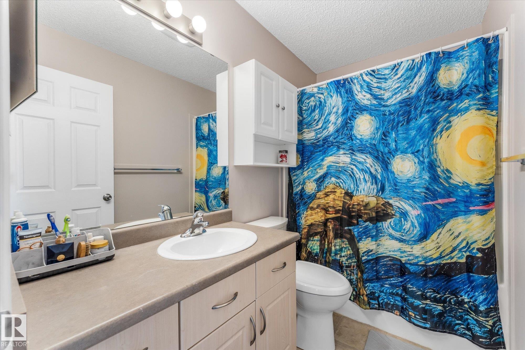 Bathroom featuring a single vanity with a laminate countertop, undermount sink, and chrome faucet - 2324 30 Avenue, Edmonton, AB