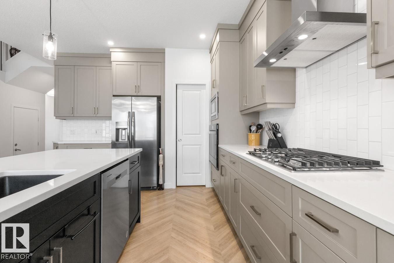 Modern kitchen featuring a gas range with stainless steel hood, built-in oven, and wood-finish herringbone flooring - 117 Paisley Gate Gate, Edmonton, AB