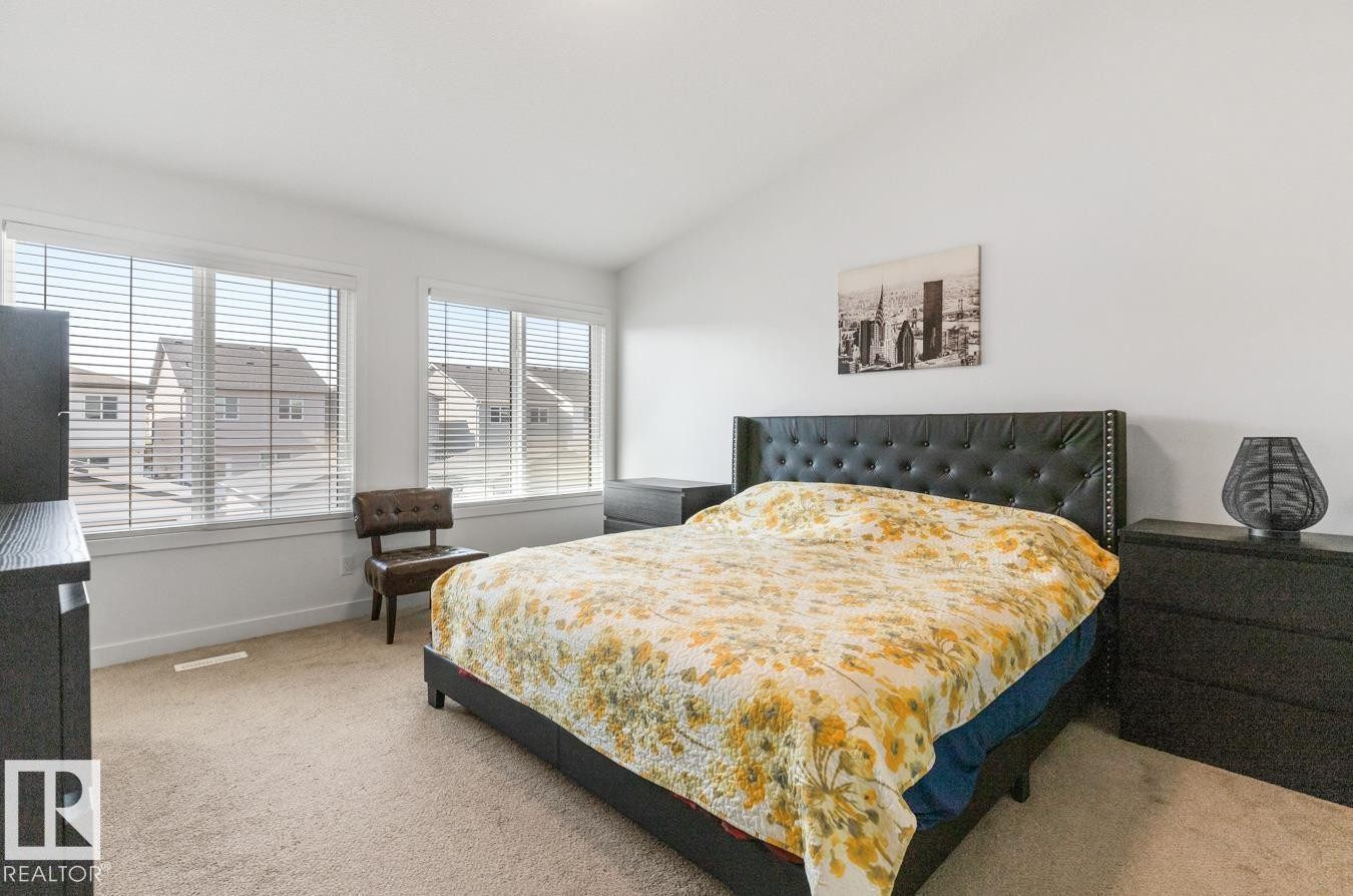 Bright bedroom featuring two large windows with blinds, light-colored carpet, and white walls - 117 Paisley Gate Gate, Edmonton, AB