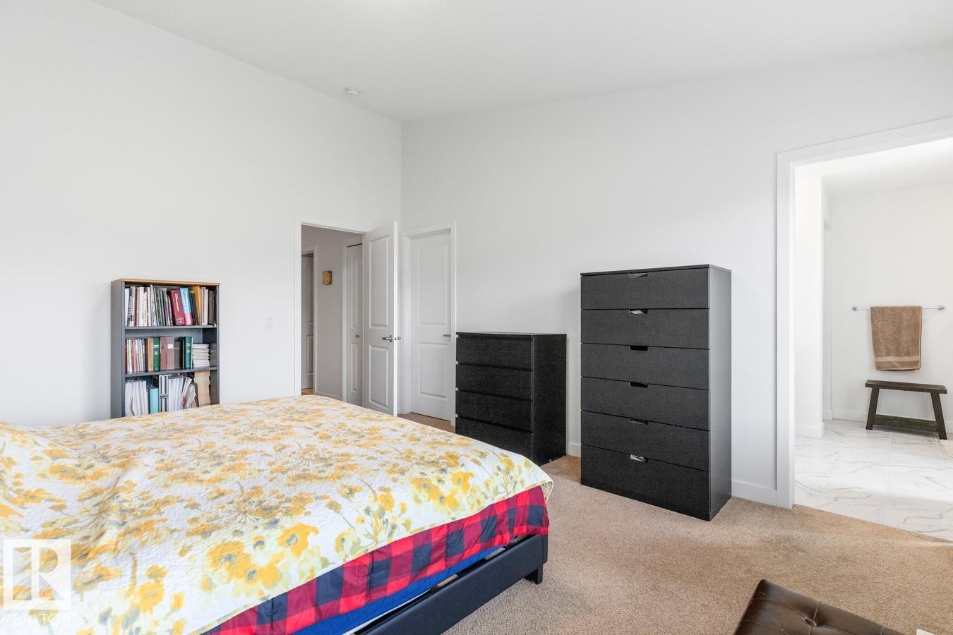 Carpeted bedroom with white walls and a doorway opening to a bathroom featuring light-colored tile flooring - 117 Paisley Gate Gate, Edmonton, AB