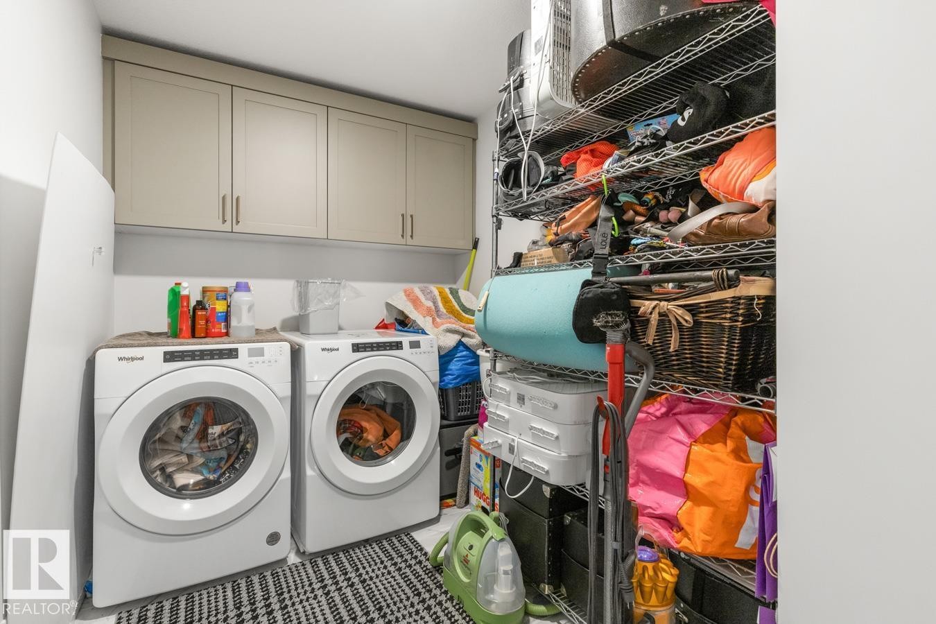 Dedicated laundry area featuring a front-loading washing machine, a front-loading dryer, and upper cabinetry - 117 Paisley Gate Gate, Edmonton, AB