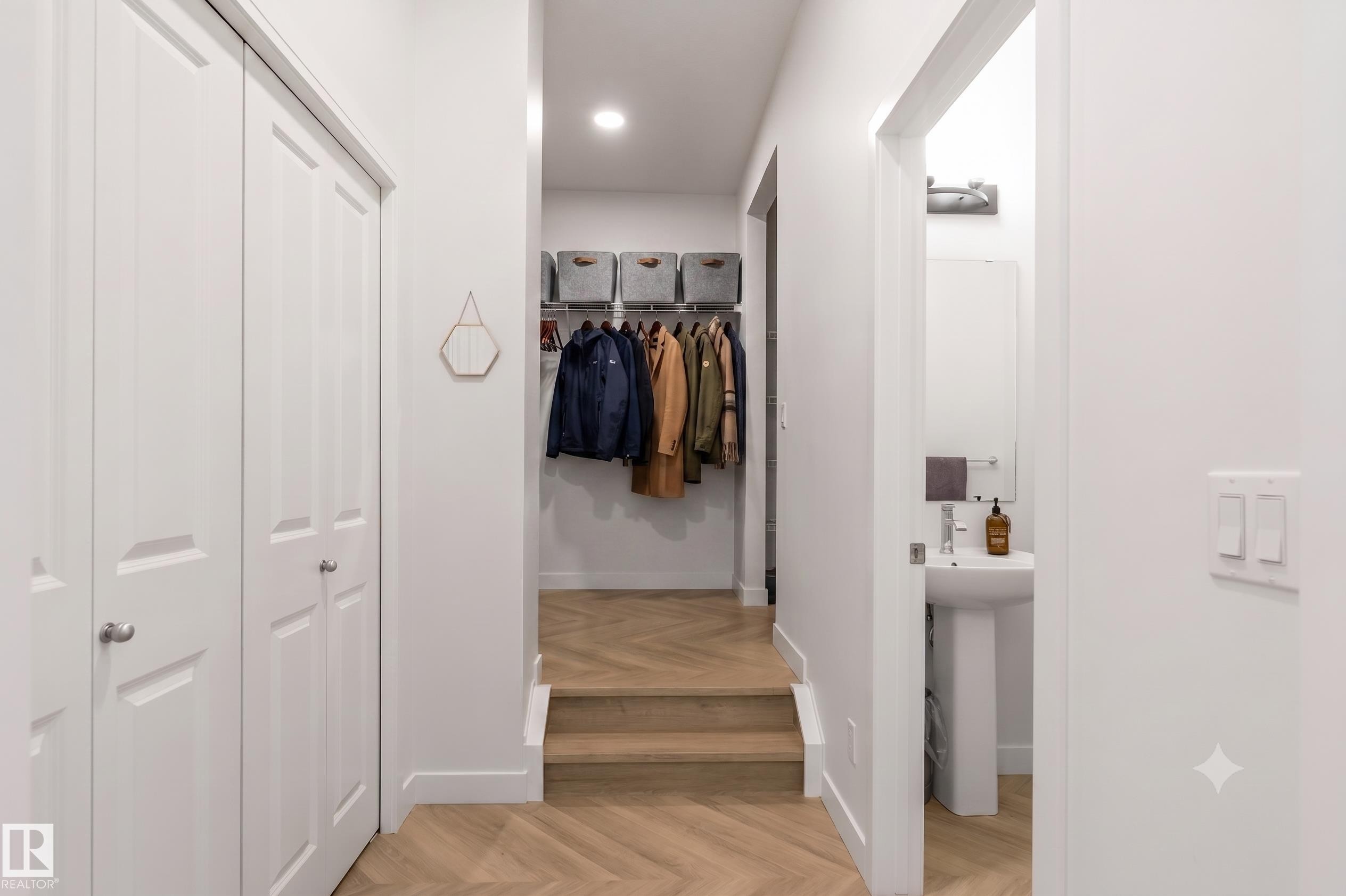 Hallway featuring light wood-finish herringbone flooring, recessed lighting, and white walls - 117 Paisley Gate Gate, Edmonton, AB