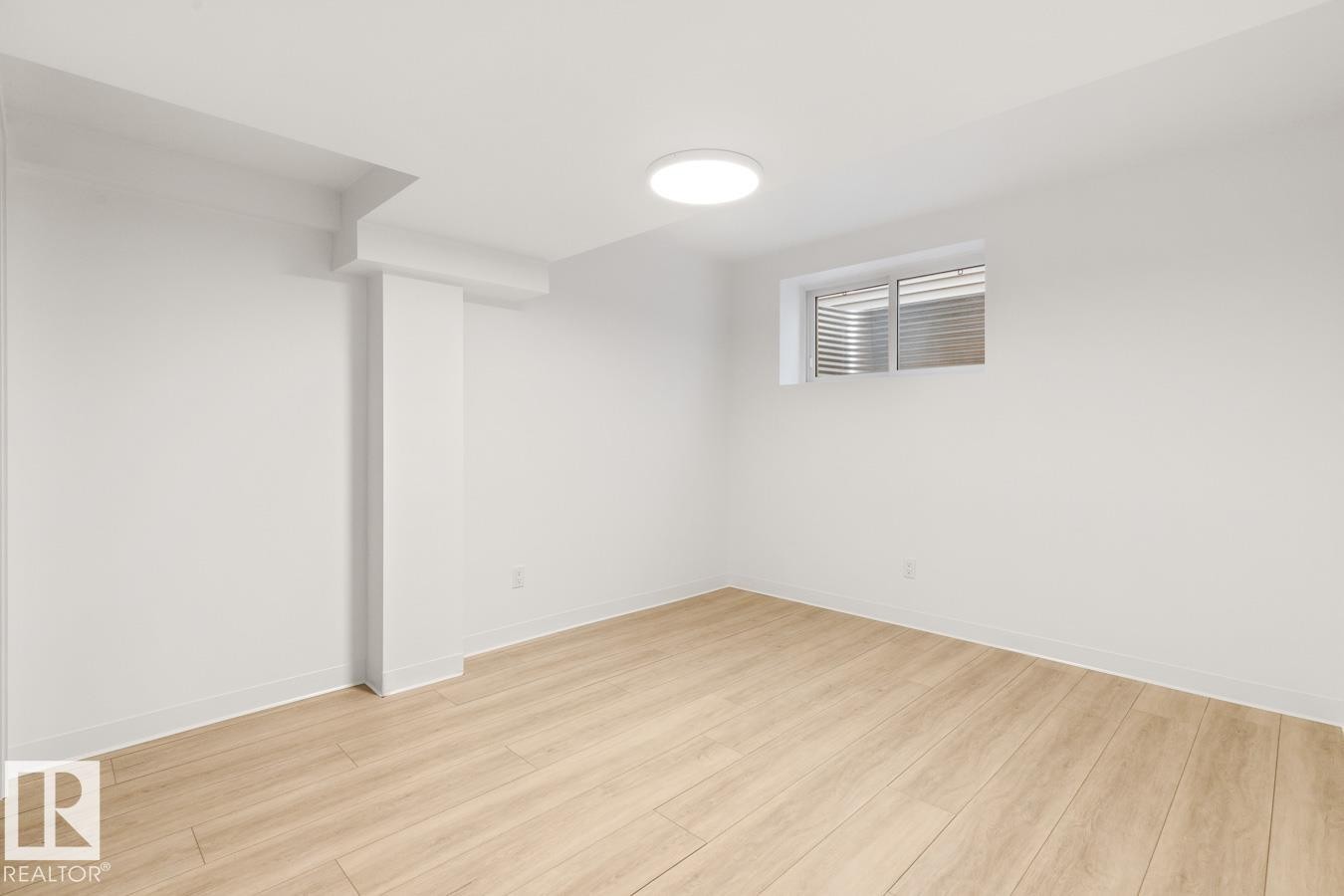 Bright room featuring wood-finish flooring, white walls, and a contemporary flush-mount ceiling light - 117 Paisley Gate Gate, Edmonton, AB