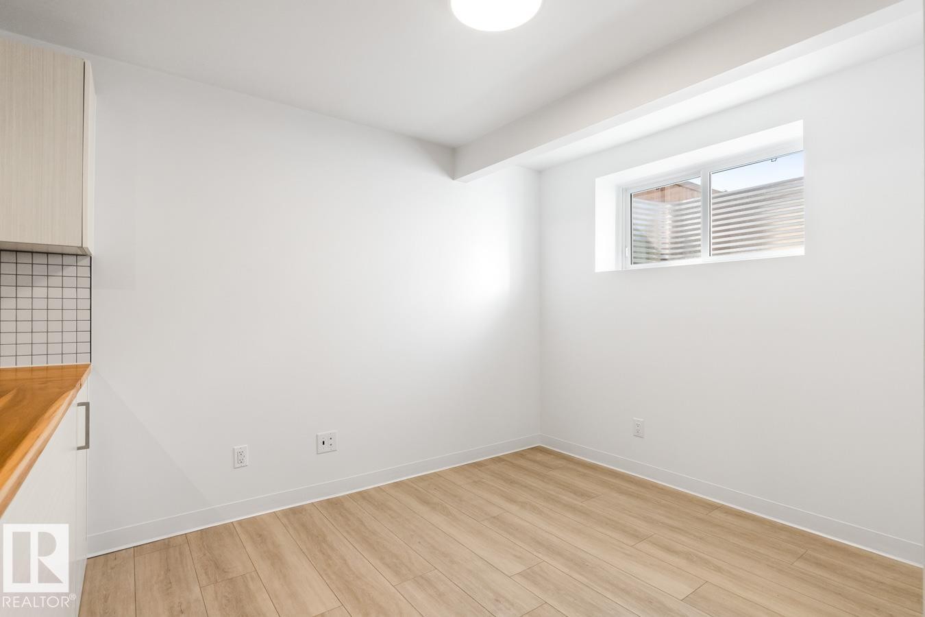 Room featuring wood-finish flooring, white baseboards, and a white fixed window with horizontal blinds - 117 Paisley Gate Gate, Edmonton, AB