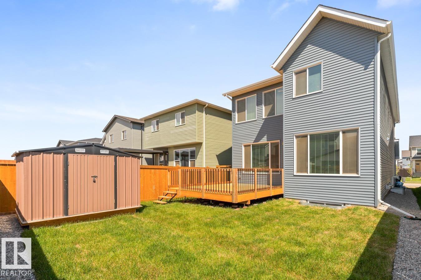 Rear exterior showcasing a wood deck with black railings, a grass lawn, and a metal storage shed - 117 Paisley Gate Gate, Edmonton, AB