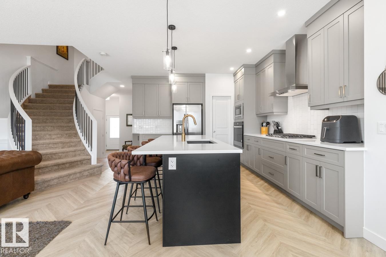 Modern kitchen featuring an island with white countertop, gray cabinetry, stainless steel appliances, and a white subway tile backsplash - 117 Paisley Gate Gate, Edmonton, AB