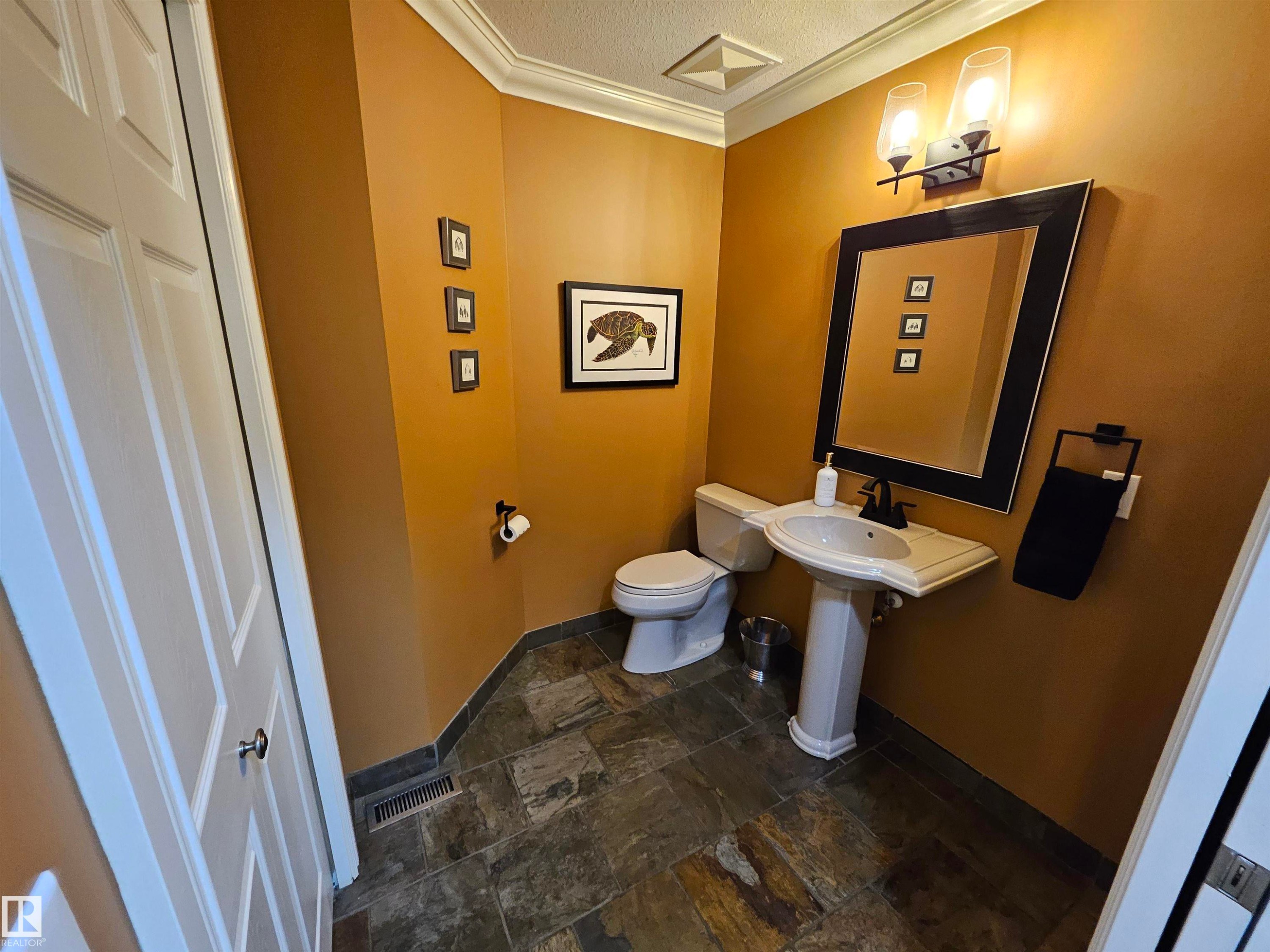Powder room featuring earthy wall tones and slate-style floor tiling - 2322 Rutherford Way, Edmonton, AB