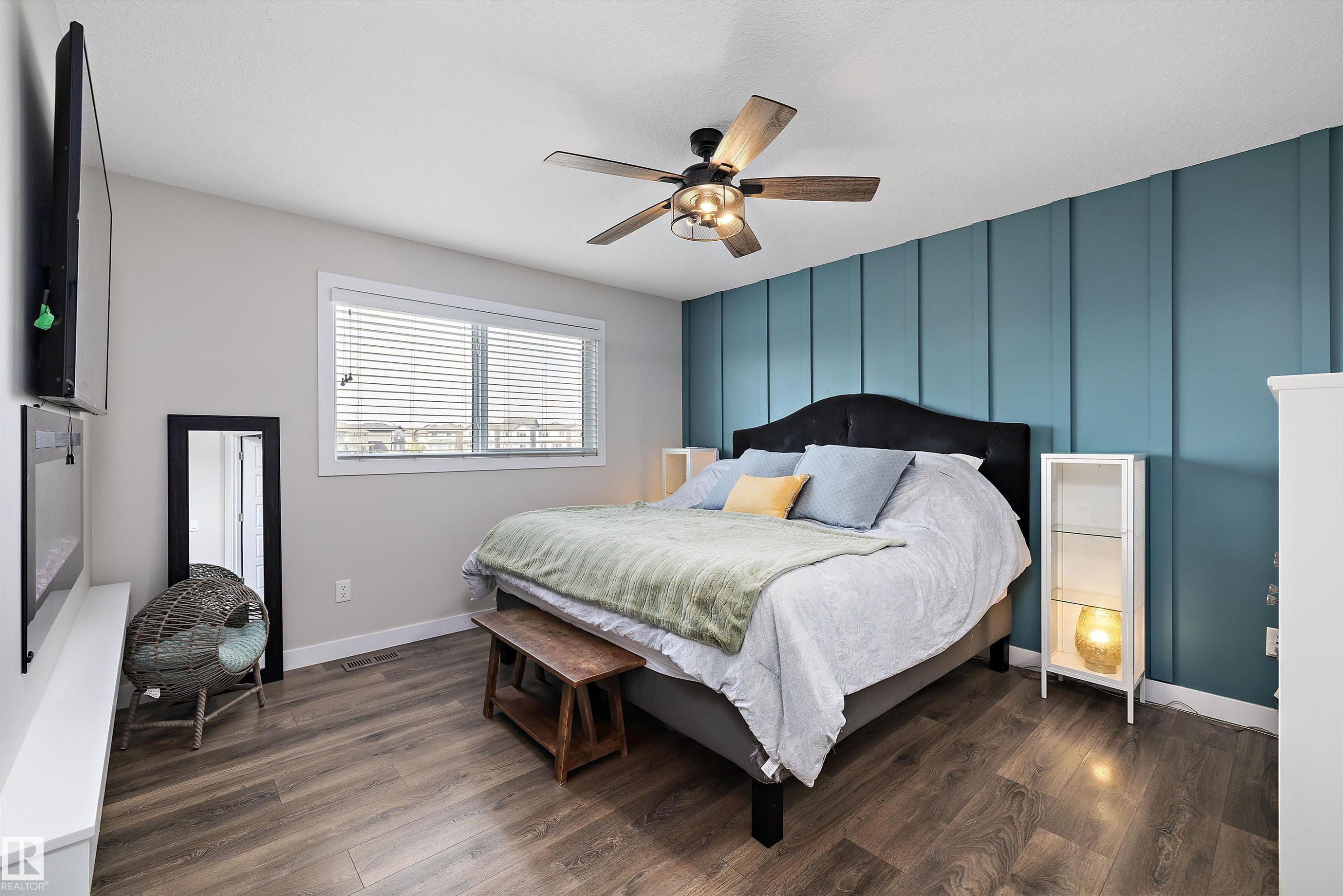 Bedroom featuring wood-finish flooring, a decorative accent wall, a ceiling fan with integrated lighting, and a double window with horizontal blinds - 363 Cy Becker Boulevard, Edmonton, AB - Indoor Photo Showing Bedroom