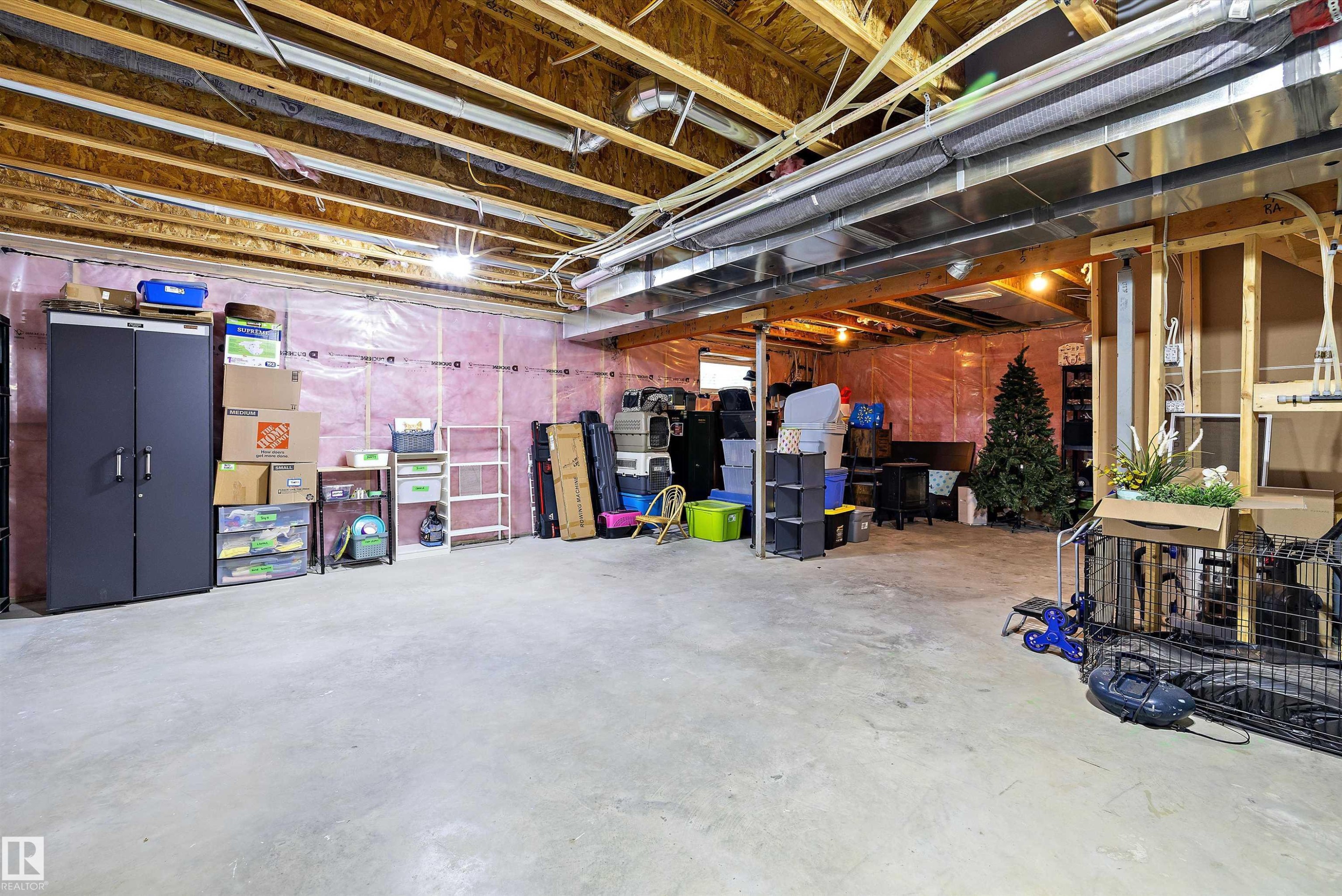 Unfinished basement featuring exposed wood joists, concrete flooring, pink insulation, and visible utility conduits - 363 Cy Becker Boulevard, Edmonton, AB - Indoor Photo Showing Basement