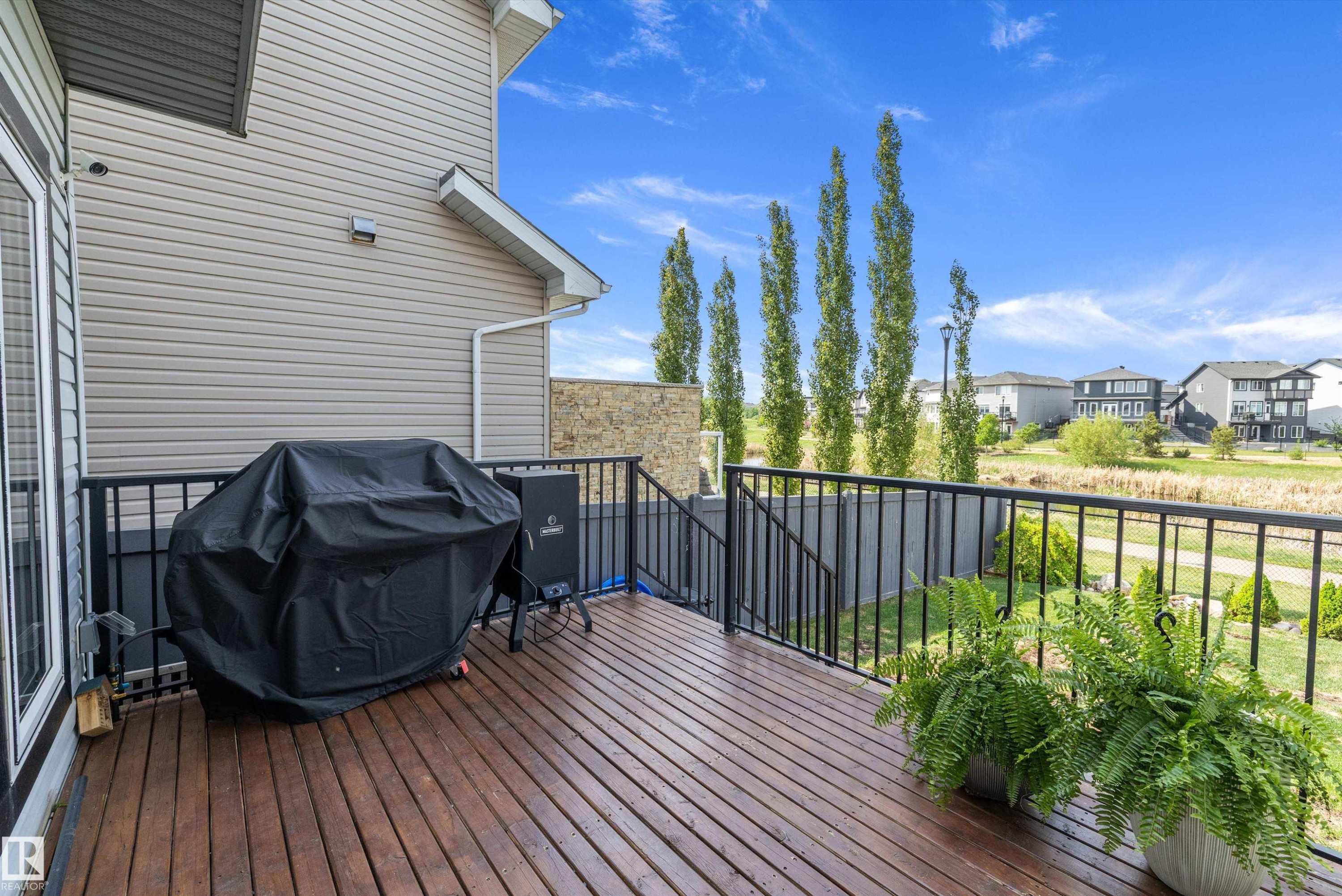 Expansive wood-finish deck featuring black metal railings and direct access to the interior via a sliding glass door - 363 Cy Becker Boulevard, Edmonton, AB - Outdoor With Deck Patio Veranda With Exterior