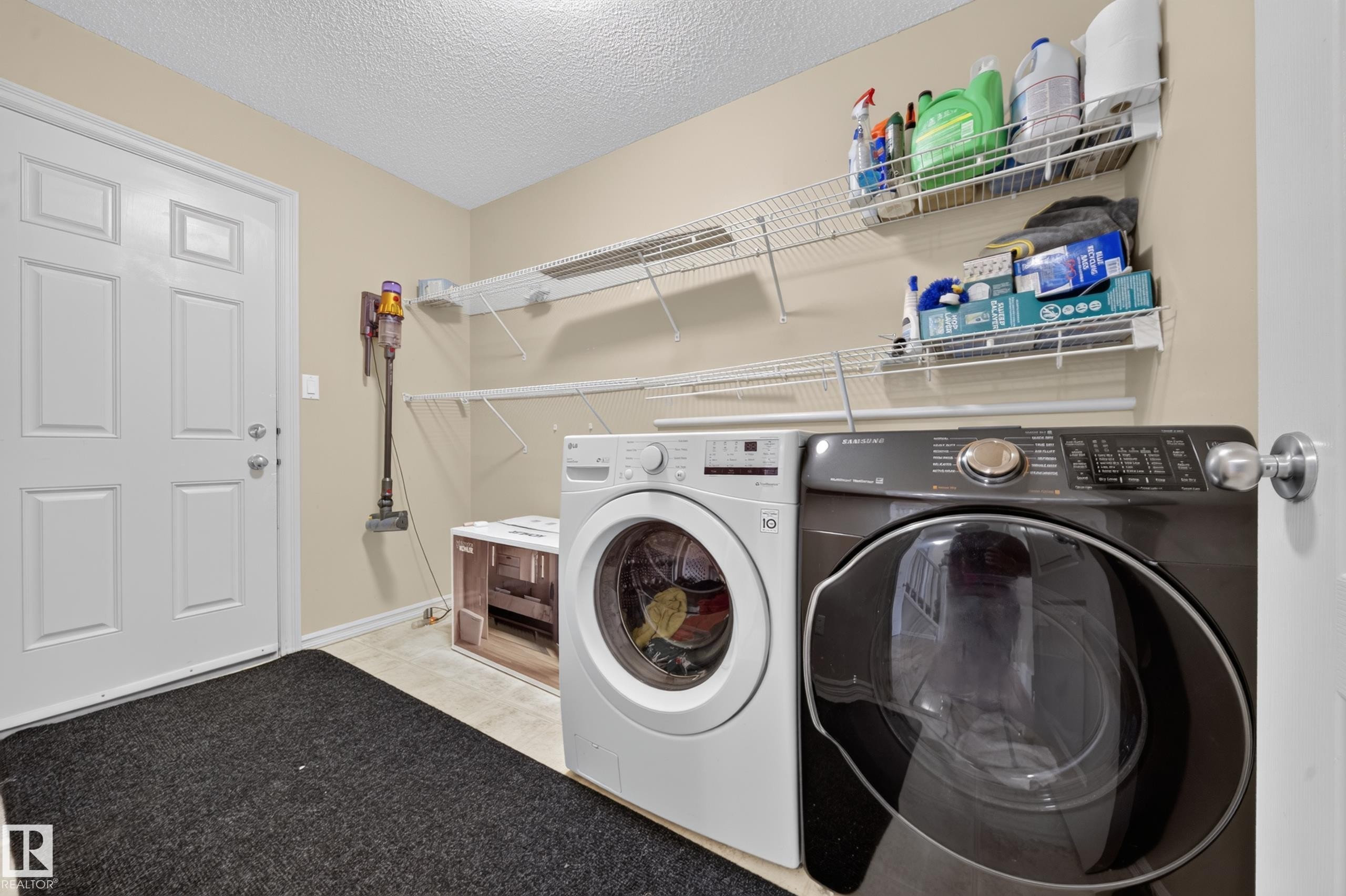 Dedicated laundry area featuring front-loading appliances, light-toned wall paint, and white wire shelving for organization - 2518 33A Avenue, Edmonton, AB