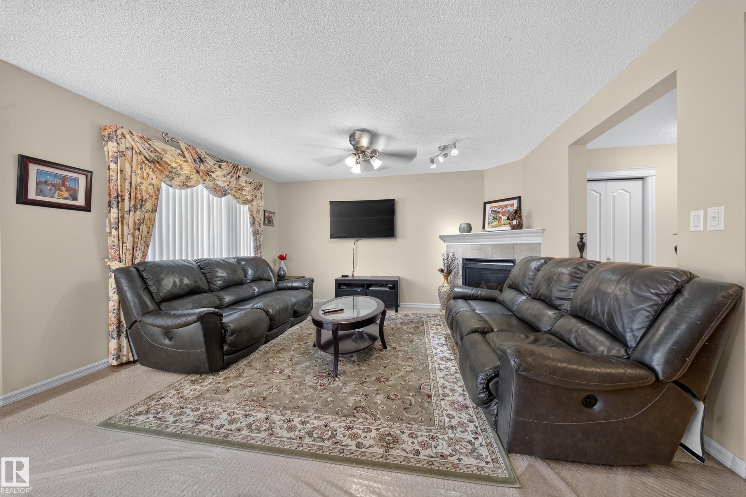 Living area featuring a central fireplace with a tiled surround and mantel - 2518 33A Avenue, Edmonton, AB