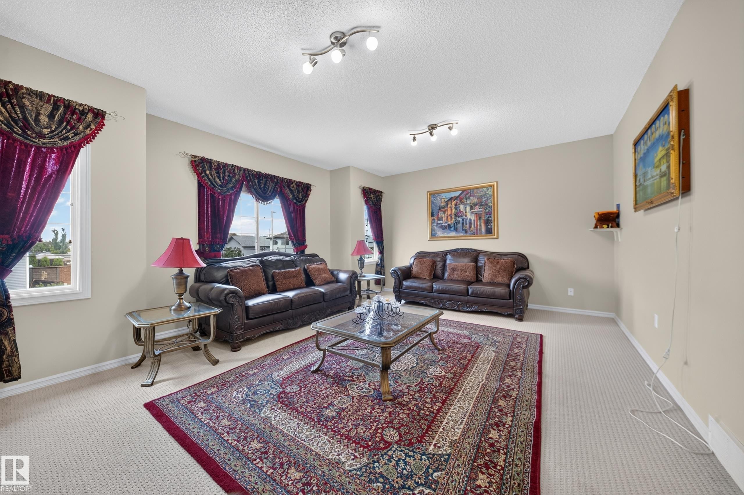 Spacious living area featuring neutral-toned walls, track lighting, and soft carpet flooring - 2518 33A Avenue, Edmonton, AB