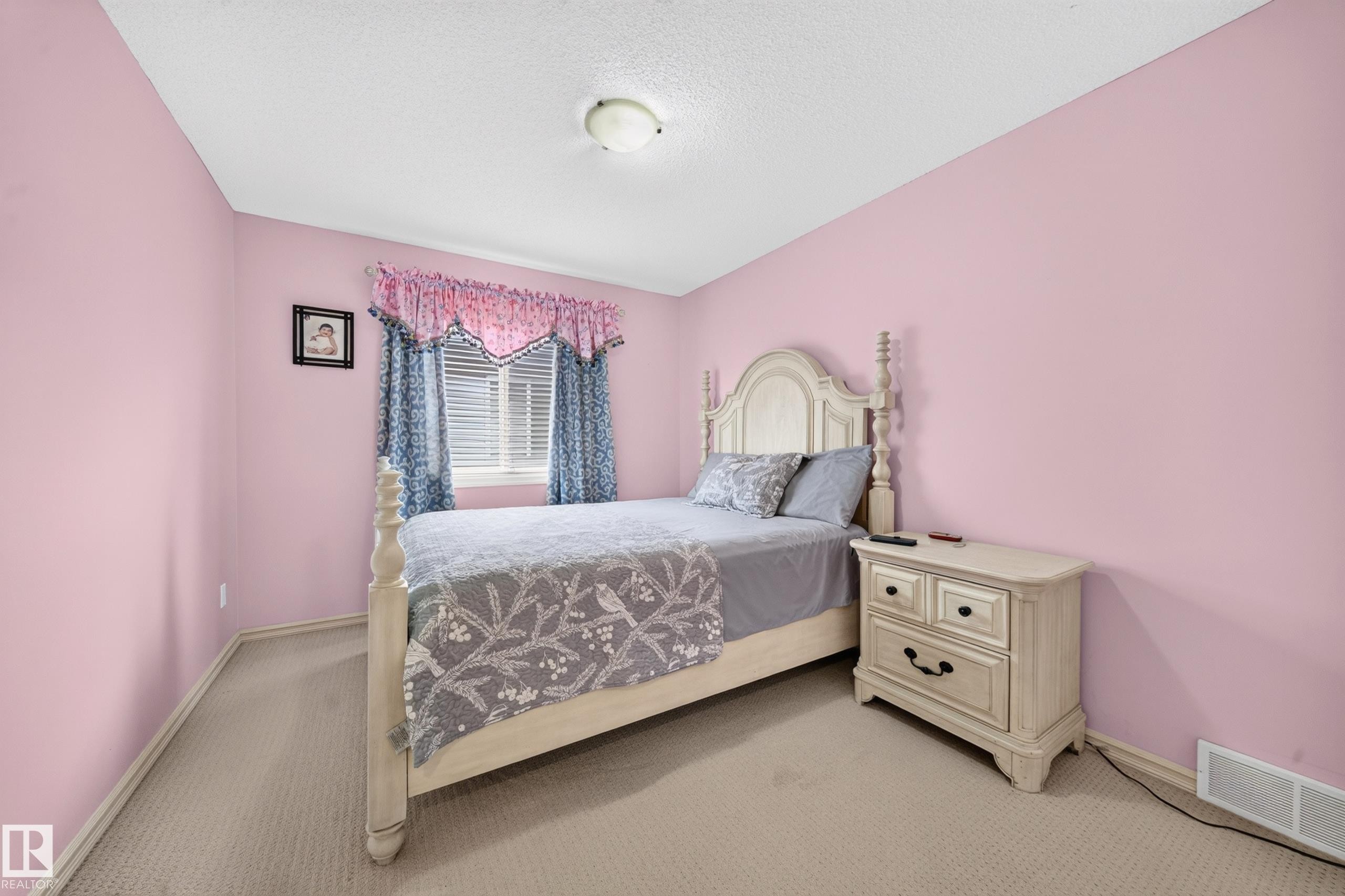 Carpeted room featuring a single window with blinds and valance, light pink walls, and a ceiling-mounted light fixture - 2518 33A Avenue, Edmonton, AB