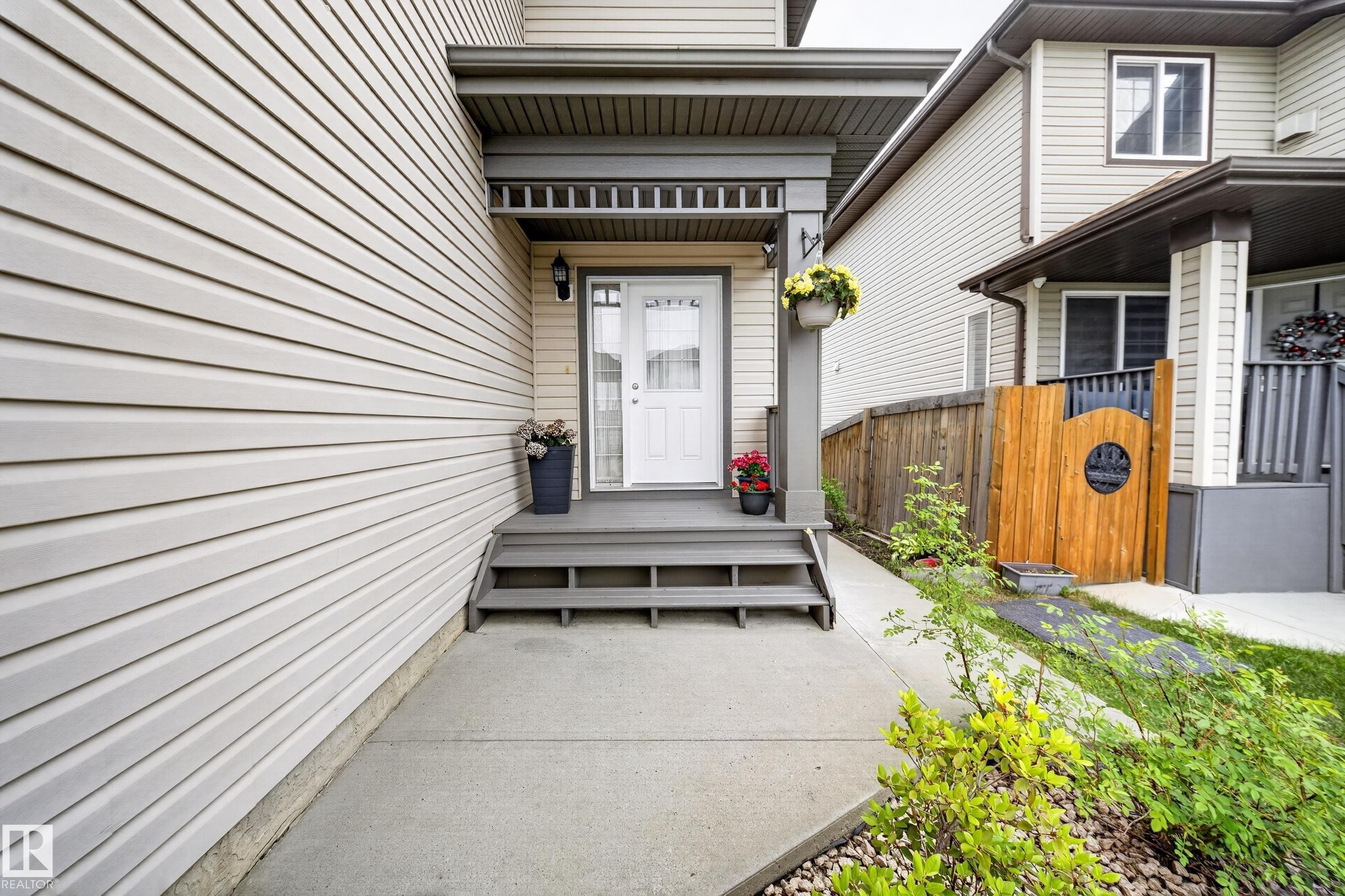 Neutral-toned siding exterior with a welcoming entryway featuring a covered porch and white front door with decorative glass - 2518 33A Avenue, Edmonton, AB