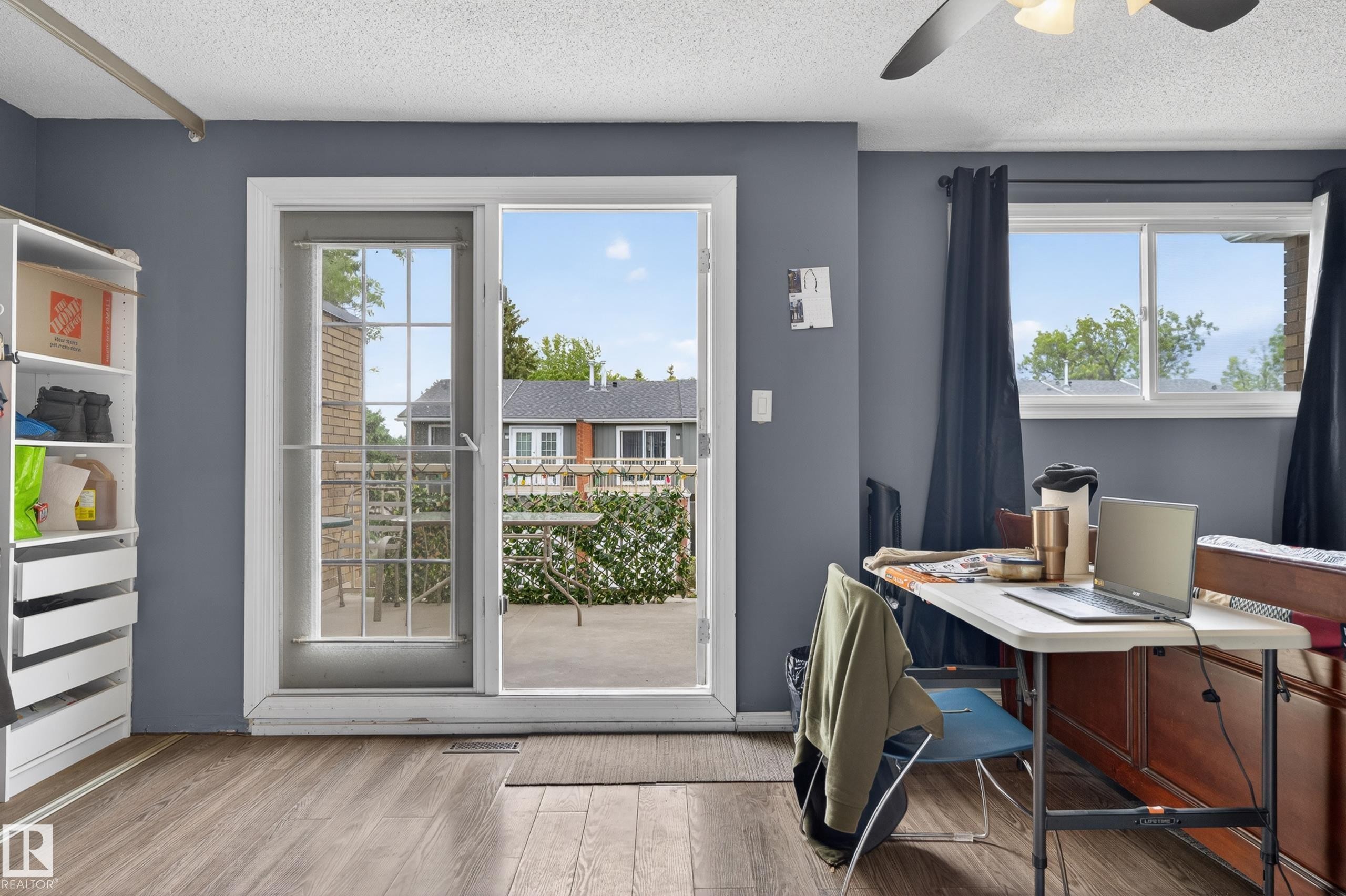 Light wood-finish flooring, a ceiling fan, and a built-in shelving unit characterize this room - 13445 40 Street Nw, Edmonton, AB
