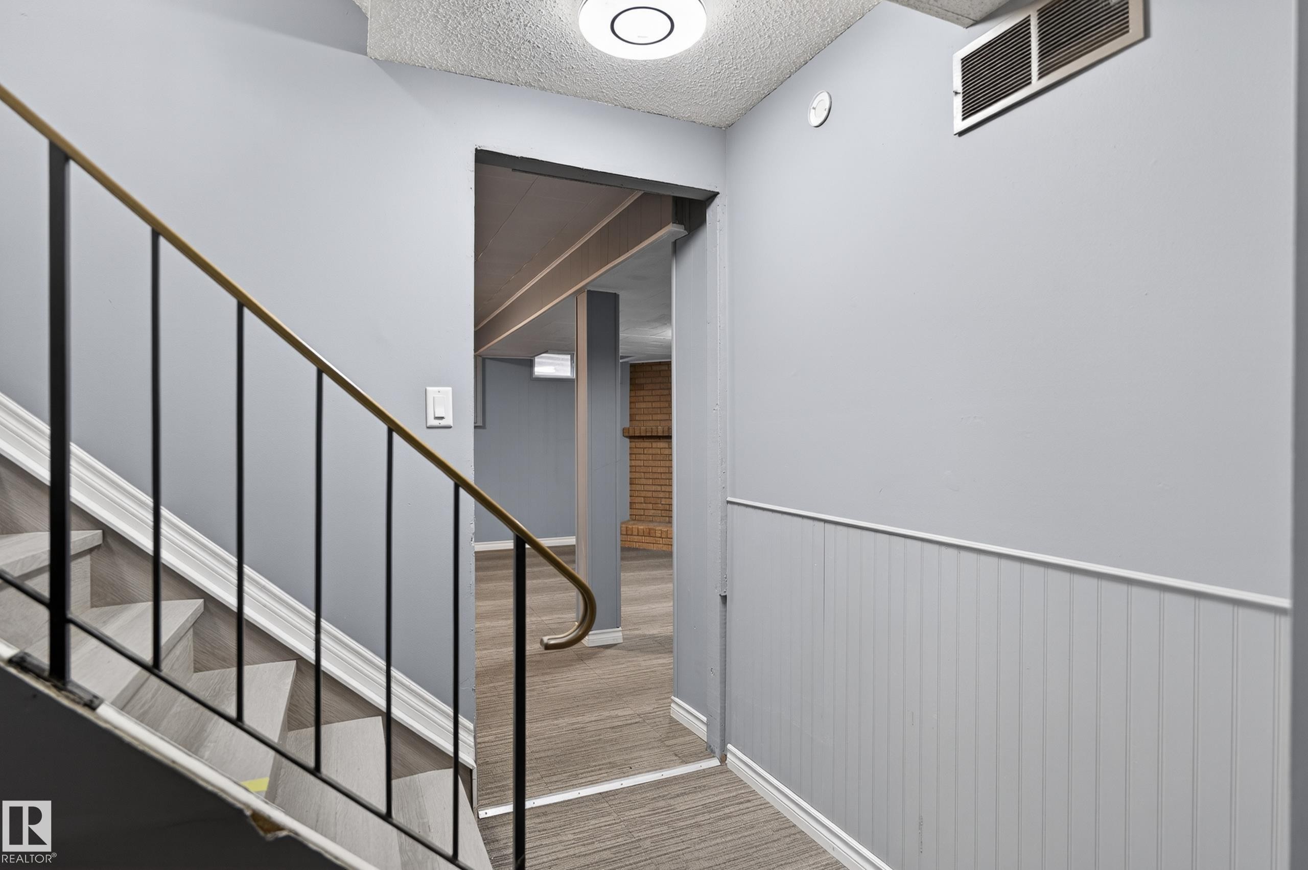 Staircase with wood-finish treads and a wrought iron handrail - 13445 40 Street Nw, Edmonton, AB