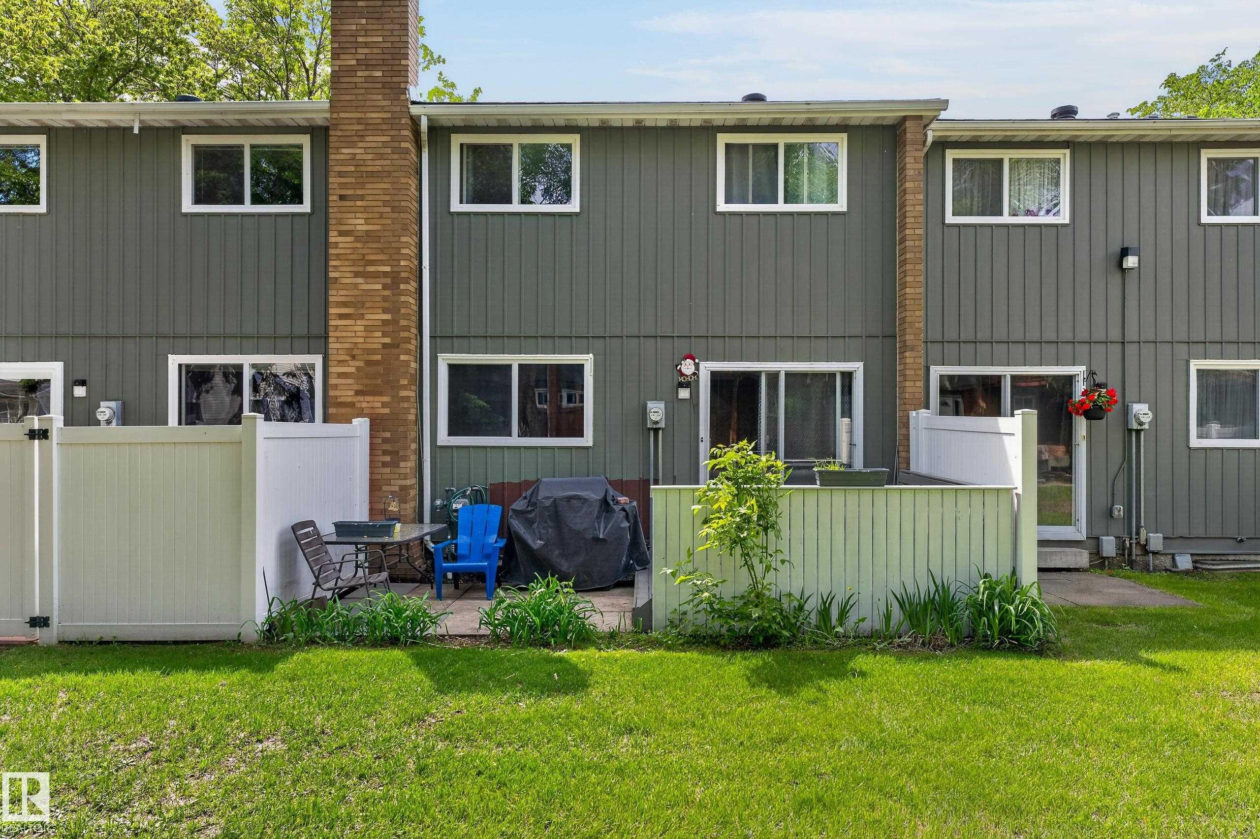 Rear exterior featuring vertical siding, multiple windows, and a brick chimney - 13445 40 Street Nw, Edmonton, AB