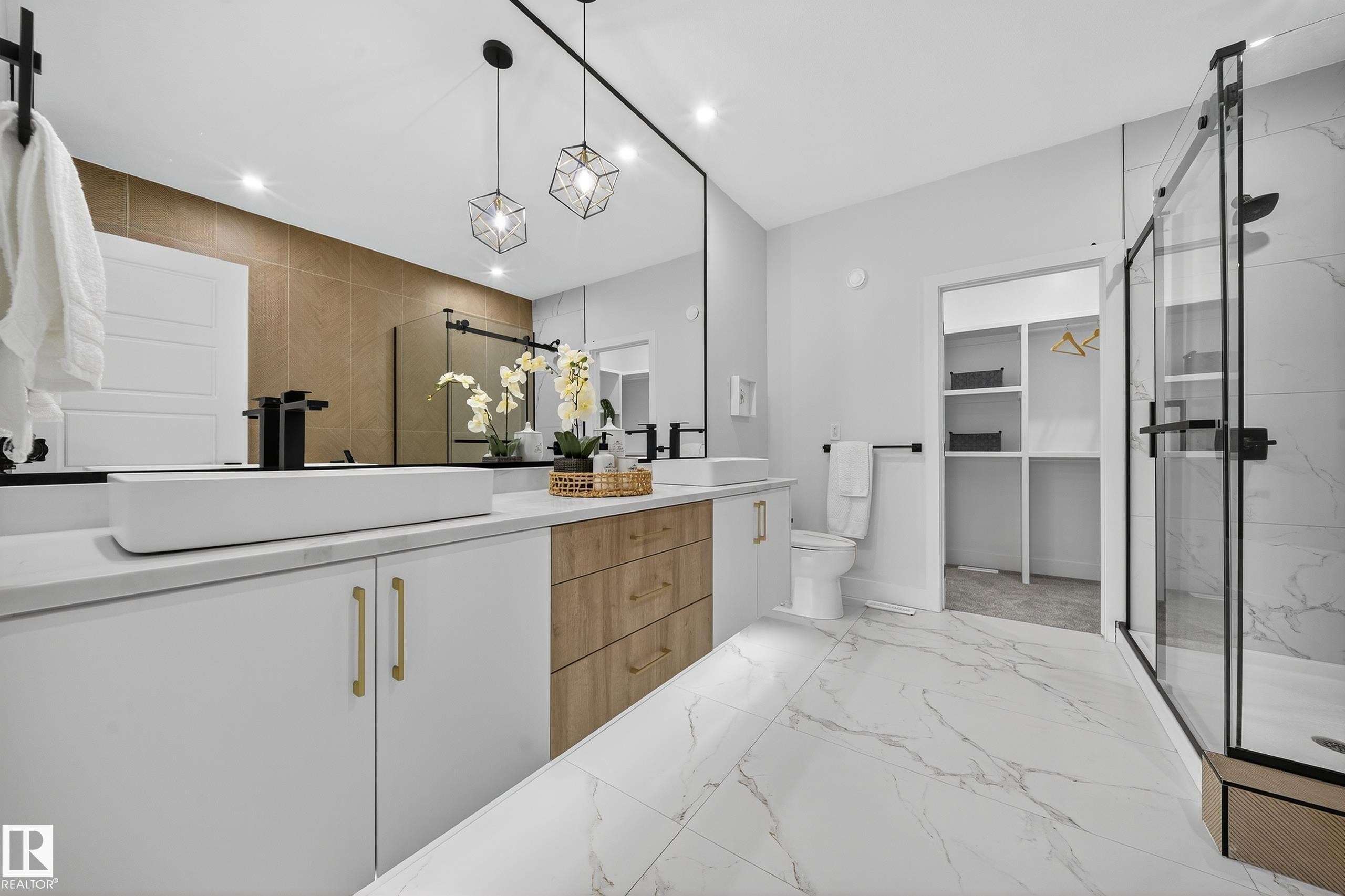 Spacious bathroom featuring a dual vanity with white cabinetry and wood-finish drawer fronts - 372 Creekside Green, Leduc, AB