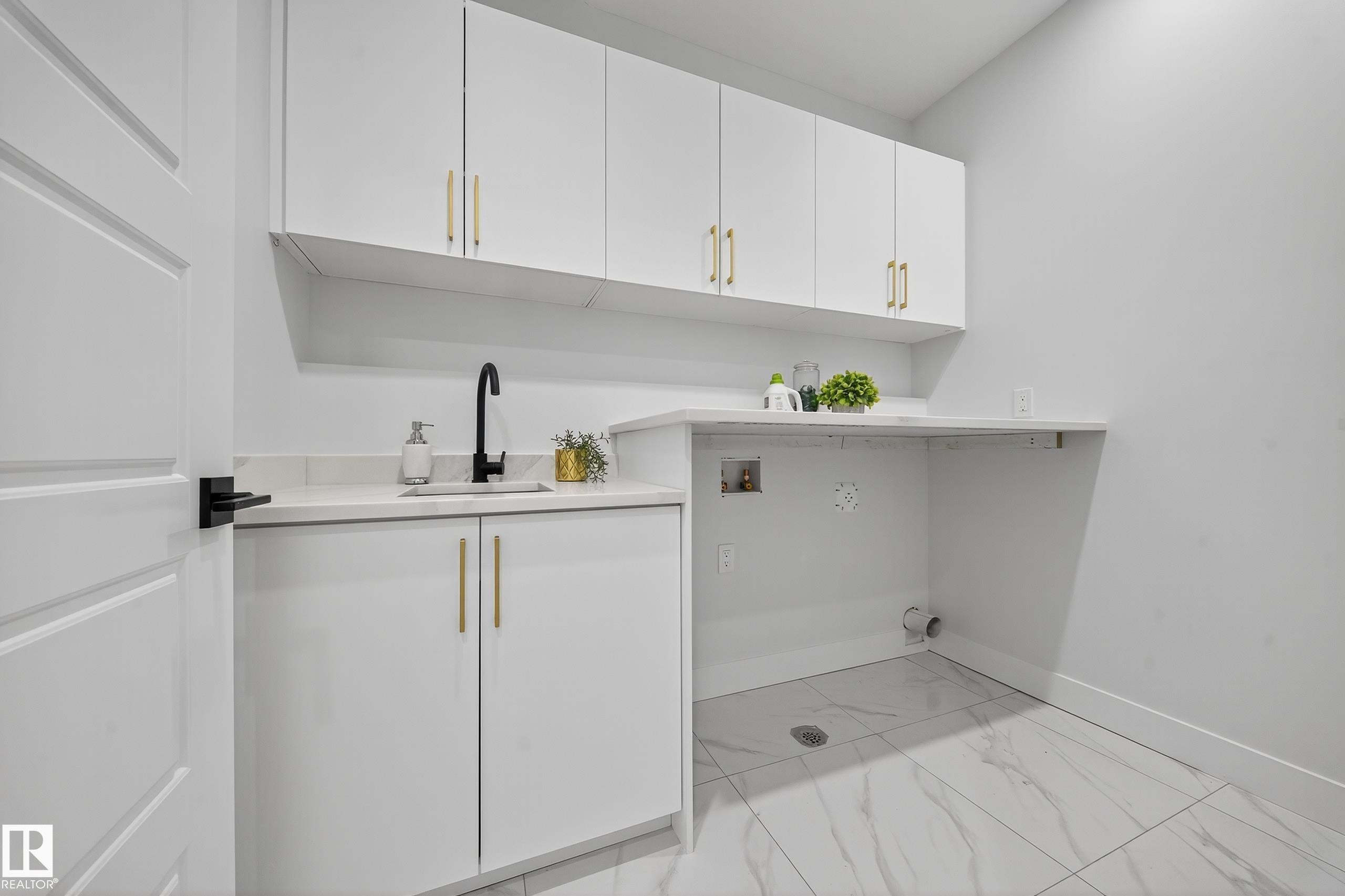 Utility room featuring white cabinetry with gold-tone hardware, a black gooseneck faucet, and an undermount sink - 372 Creekside Green, Leduc, AB