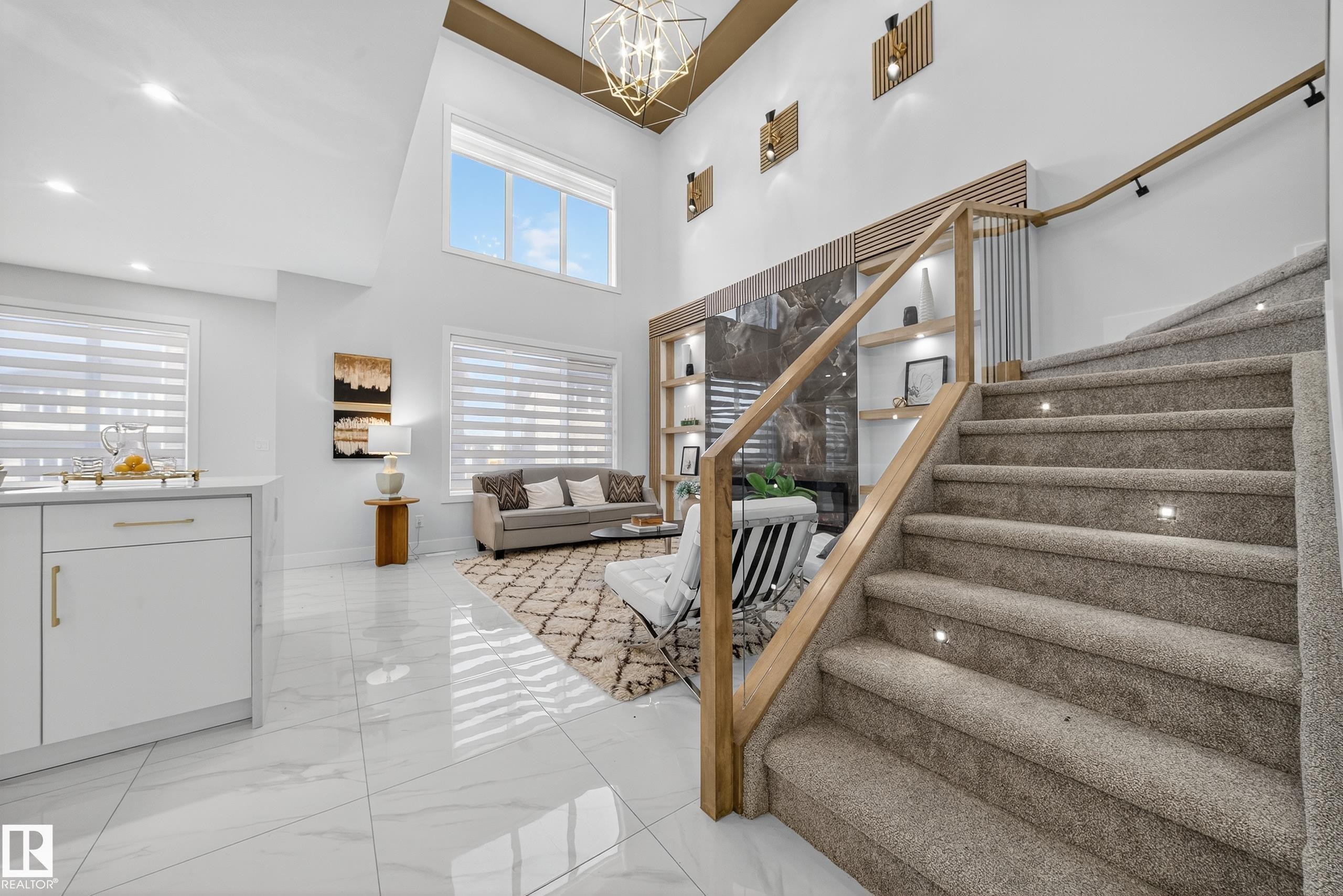 Two-story living area featuring a prominent carpeted staircase with integrated step lighting and wood-finish handrails - 372 Creekside Green, Leduc, AB