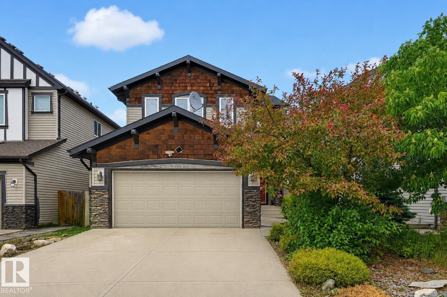Two-story property featuring a prominent garage, a concrete driveway, and stone veneer accents - 21928 97 Avenue Nw, Edmonton, AB - Outdoor