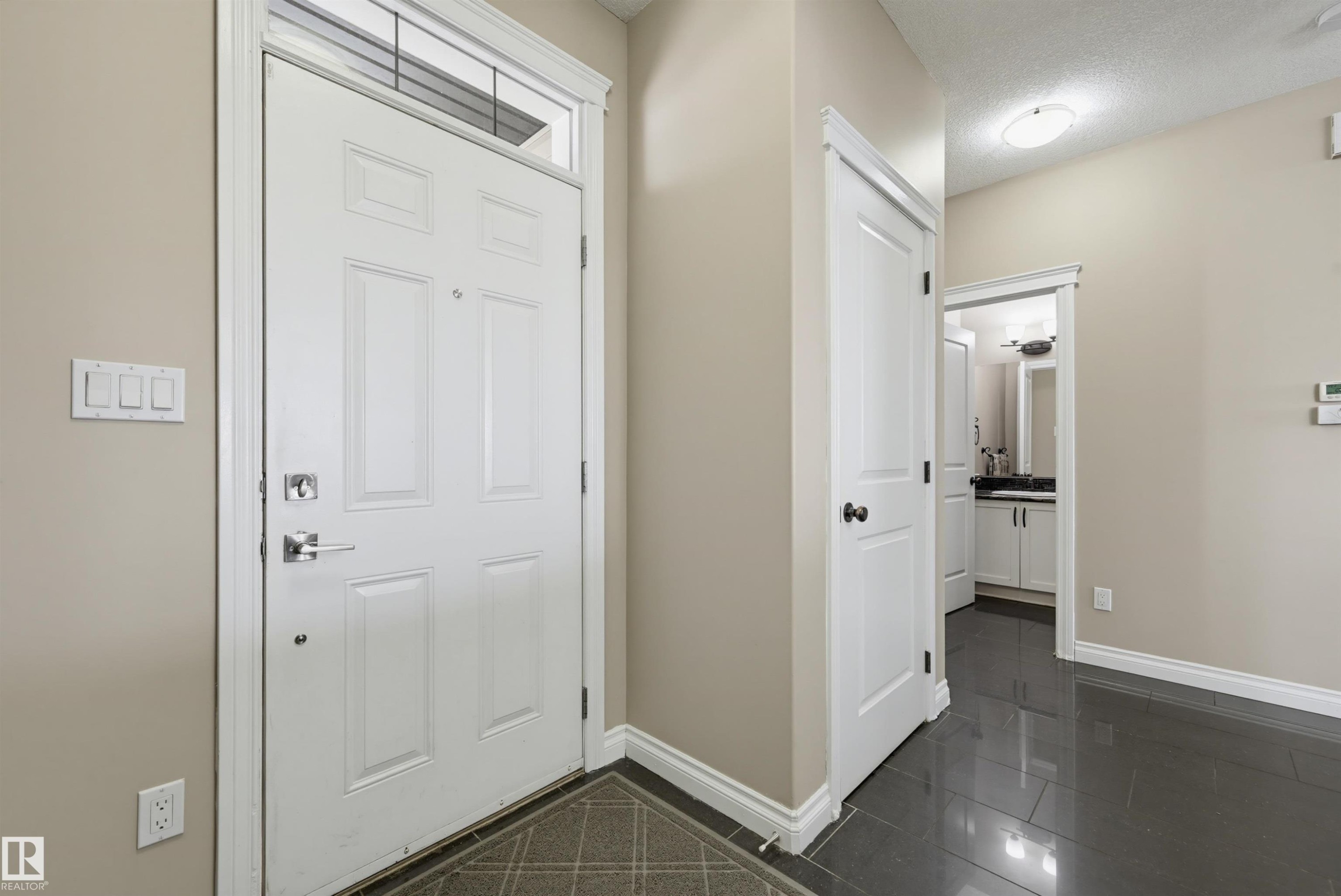 Entryway featuring a white paneled door with transom, chrome hardware, light neutral walls, and dark glossy tile flooring - 21928 97 Avenue Nw, Edmonton, AB - Indoor Photo Showing Other Room