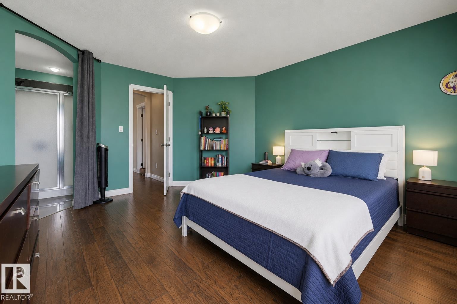 Spacious room featuring wood-finish flooring, vibrant green walls, and a recessed shower enclosure with a frosted glass door - 21928 97 Avenue Nw, Edmonton, AB - Indoor Photo Showing Bedroom