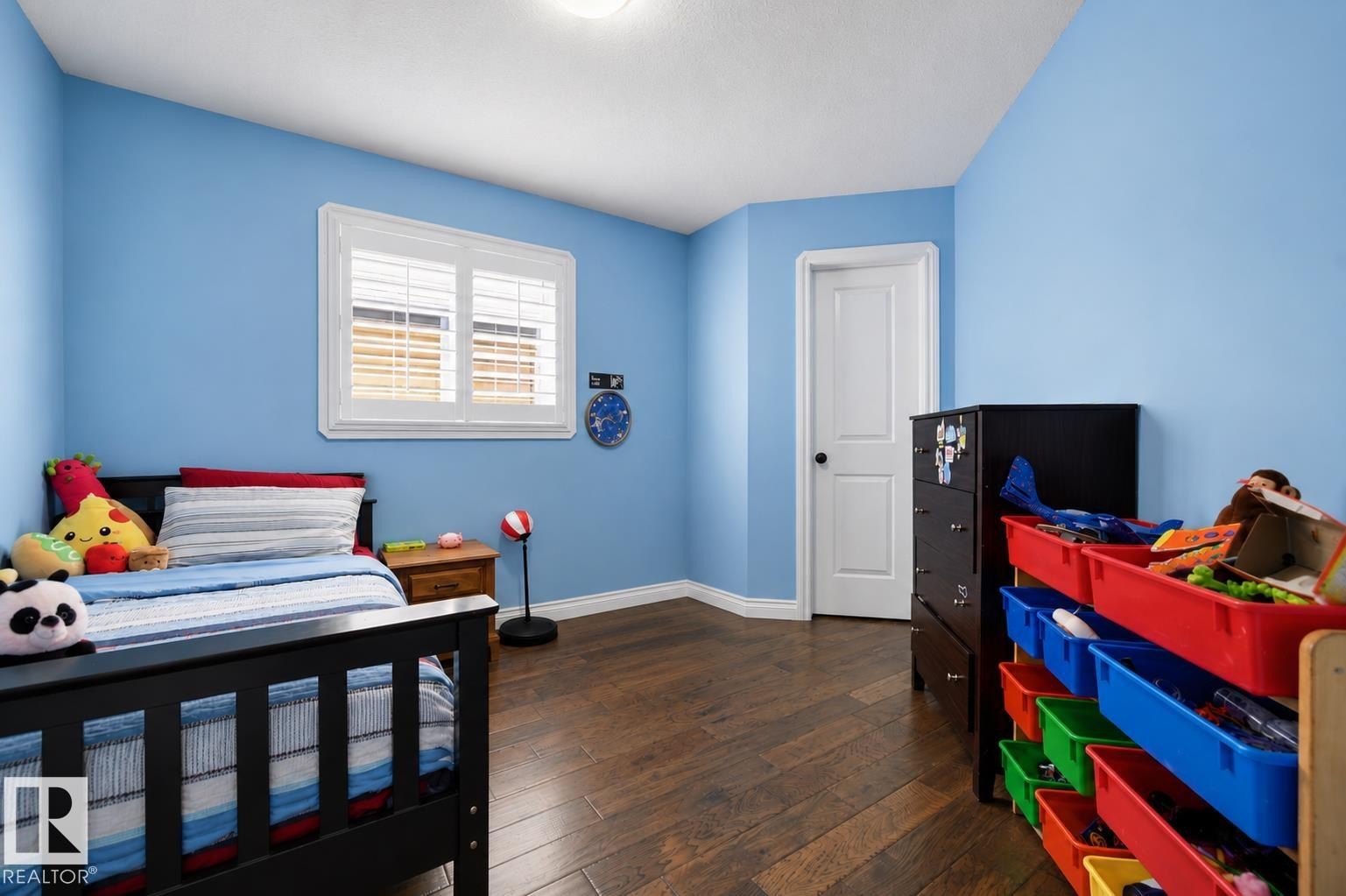Room featuring wood-finish flooring, a single window with white plantation shutters, and light blue walls - 21928 97 Avenue Nw, Edmonton, AB - Indoor Photo Showing Bedroom