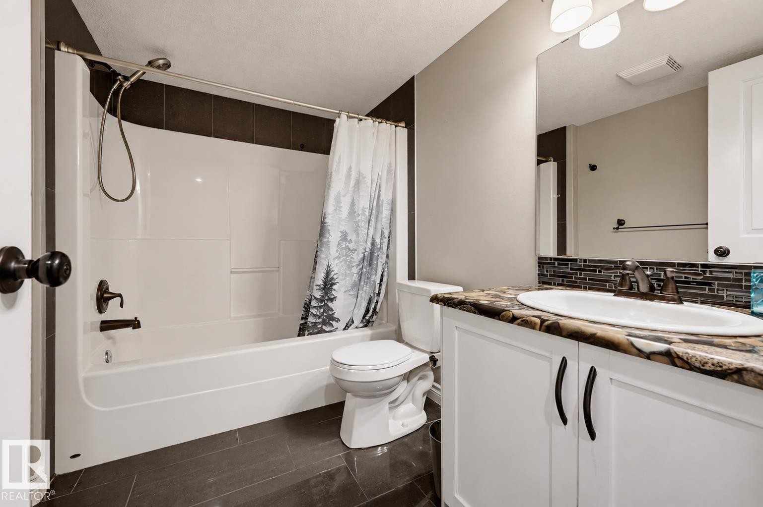 Bathroom featuring a white tub/shower combination, dark bronze fixtures, and a vanity with a patterned countertop - 21928 97 Avenue Nw, Edmonton, AB - Indoor Photo Showing Bathroom