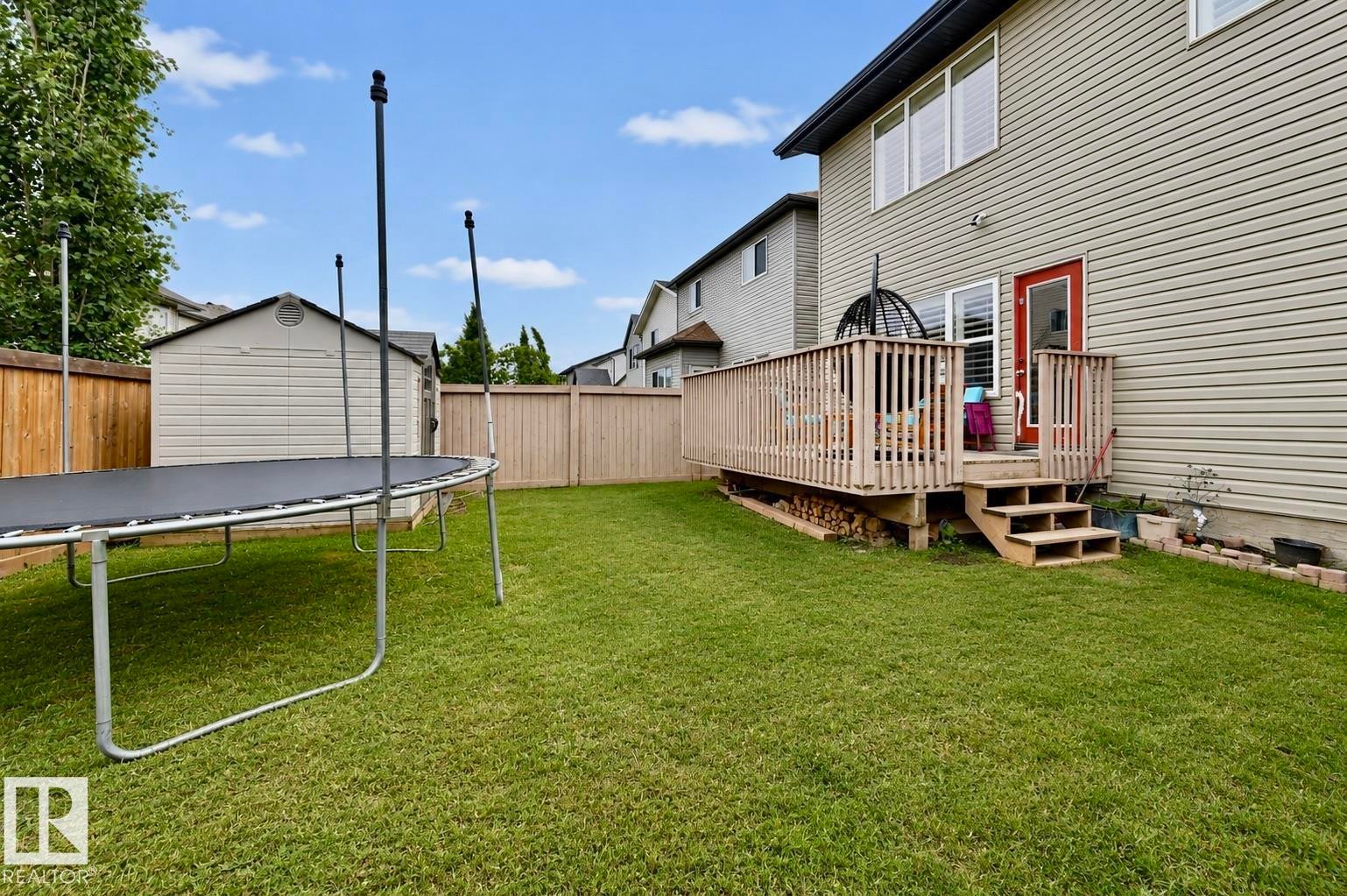 Expansive backyard featuring a manicured lawn, a full-height wood fence, a detached storage shed, a wood deck with steps, and exterior siding - 21928 97 Avenue Nw, Edmonton, AB - Outdoor With Deck Patio Veranda